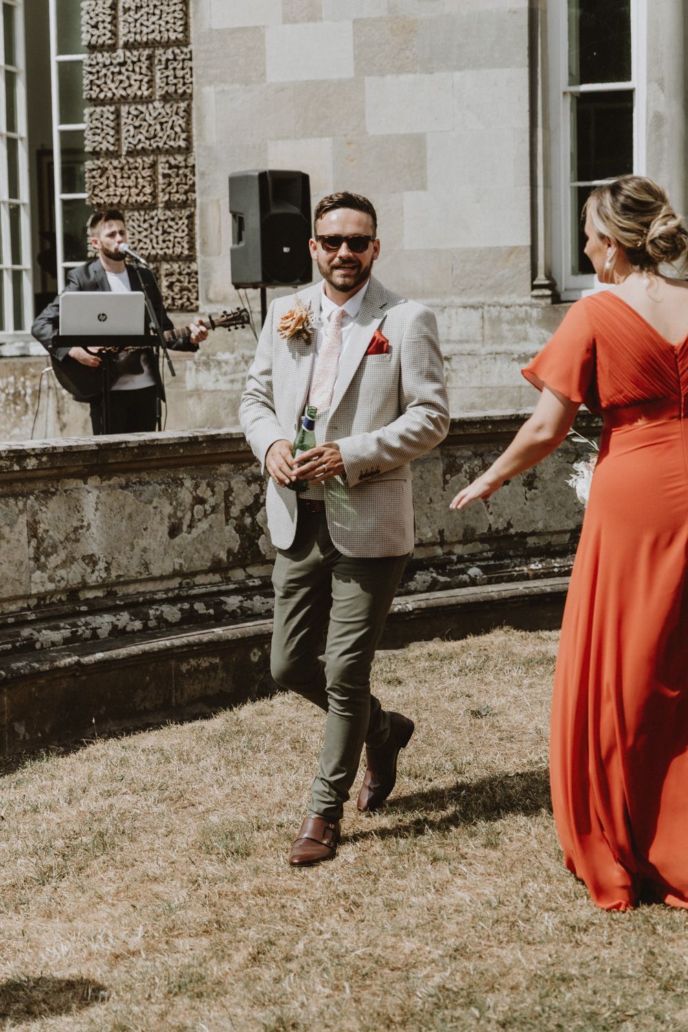 Wedding party members dancing and celebrating outdoors on a sunny day.