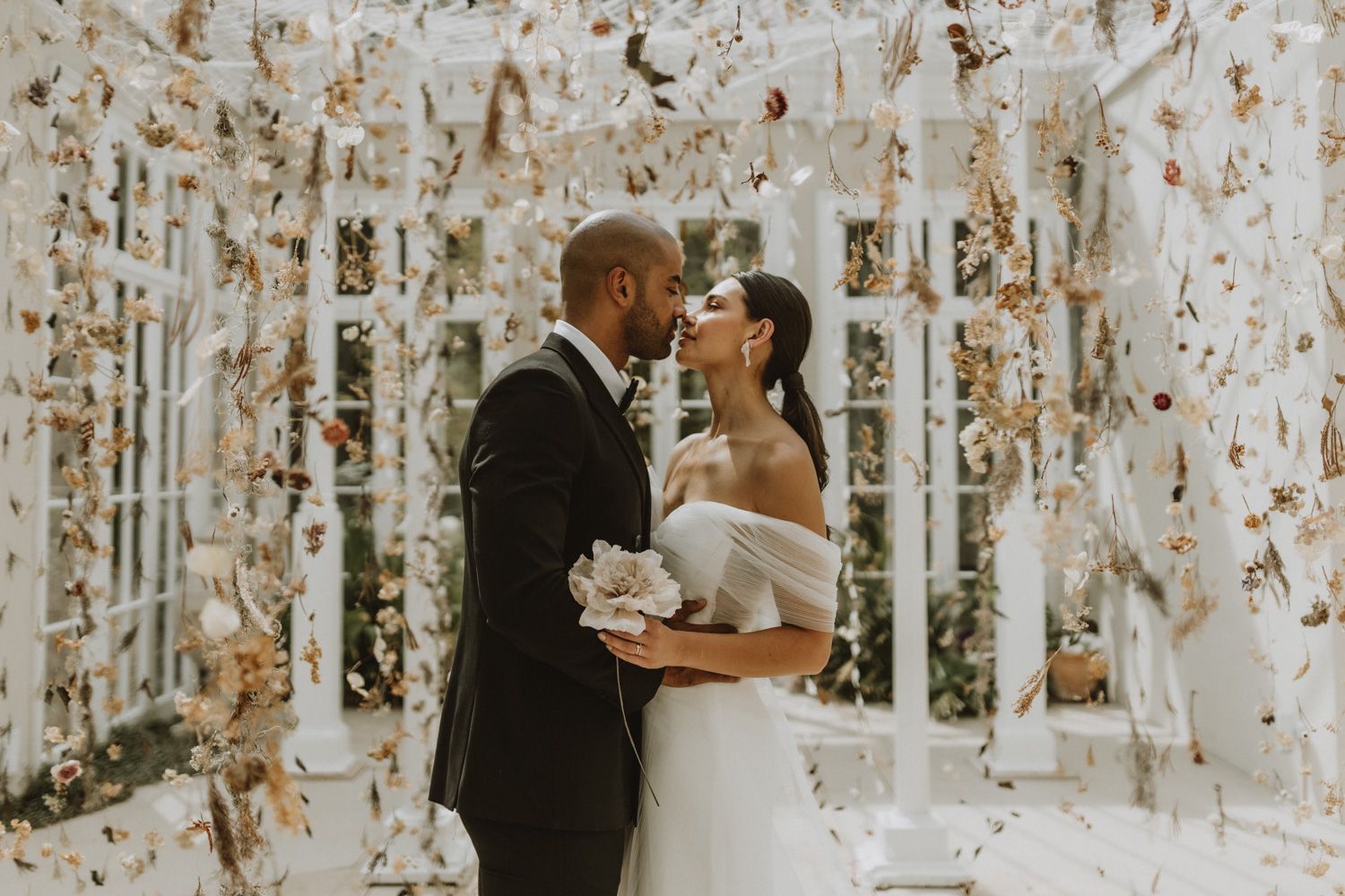 A romantic wedding ceremony moment in a conservatory filled with floral decor.