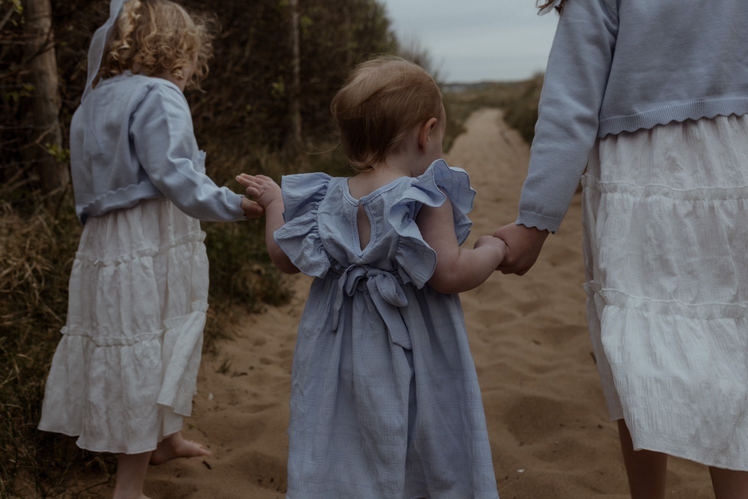 People in light colored dresses standing together outdoors.