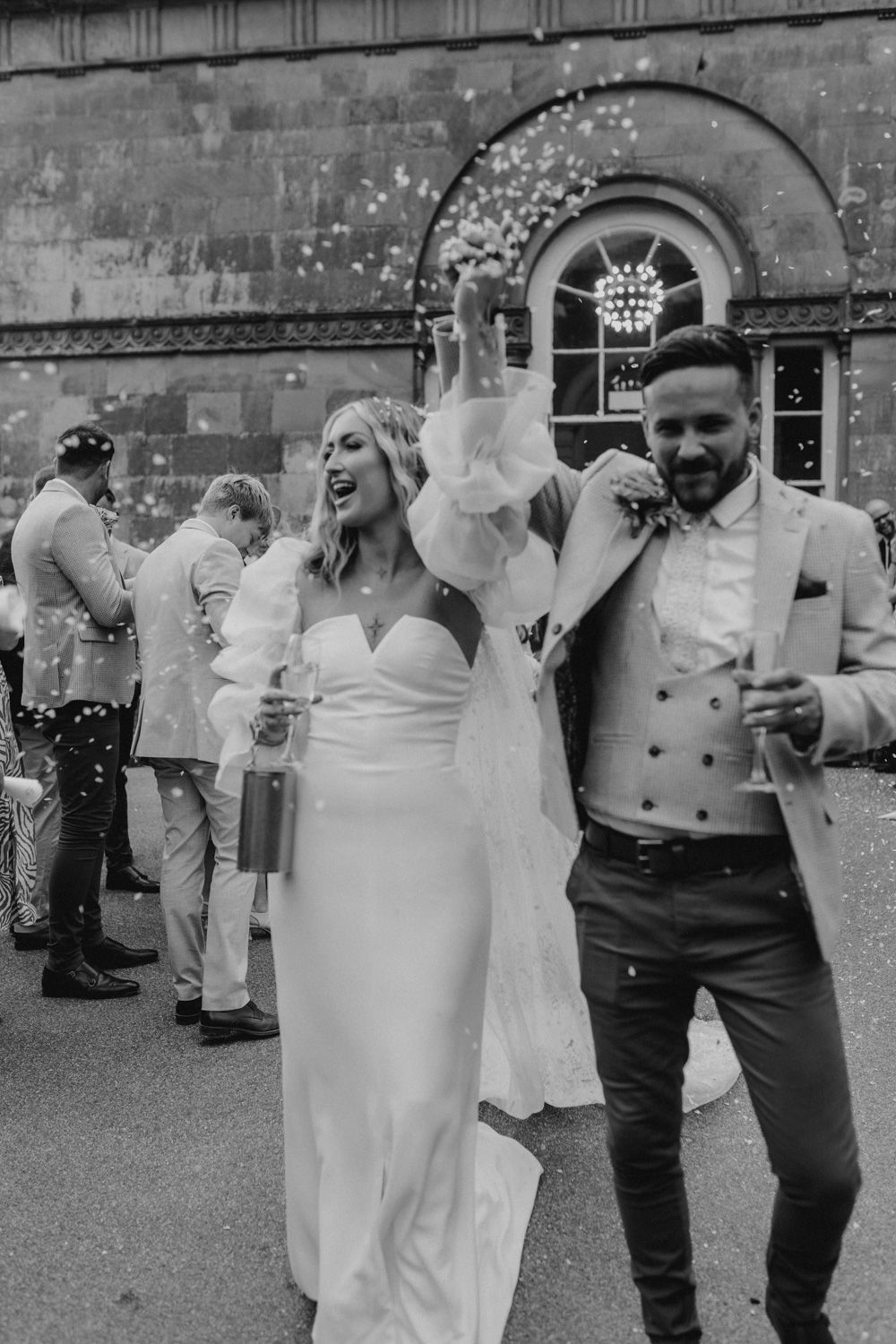 Black and white capture of joyous celebration with confetti outside historic venue.