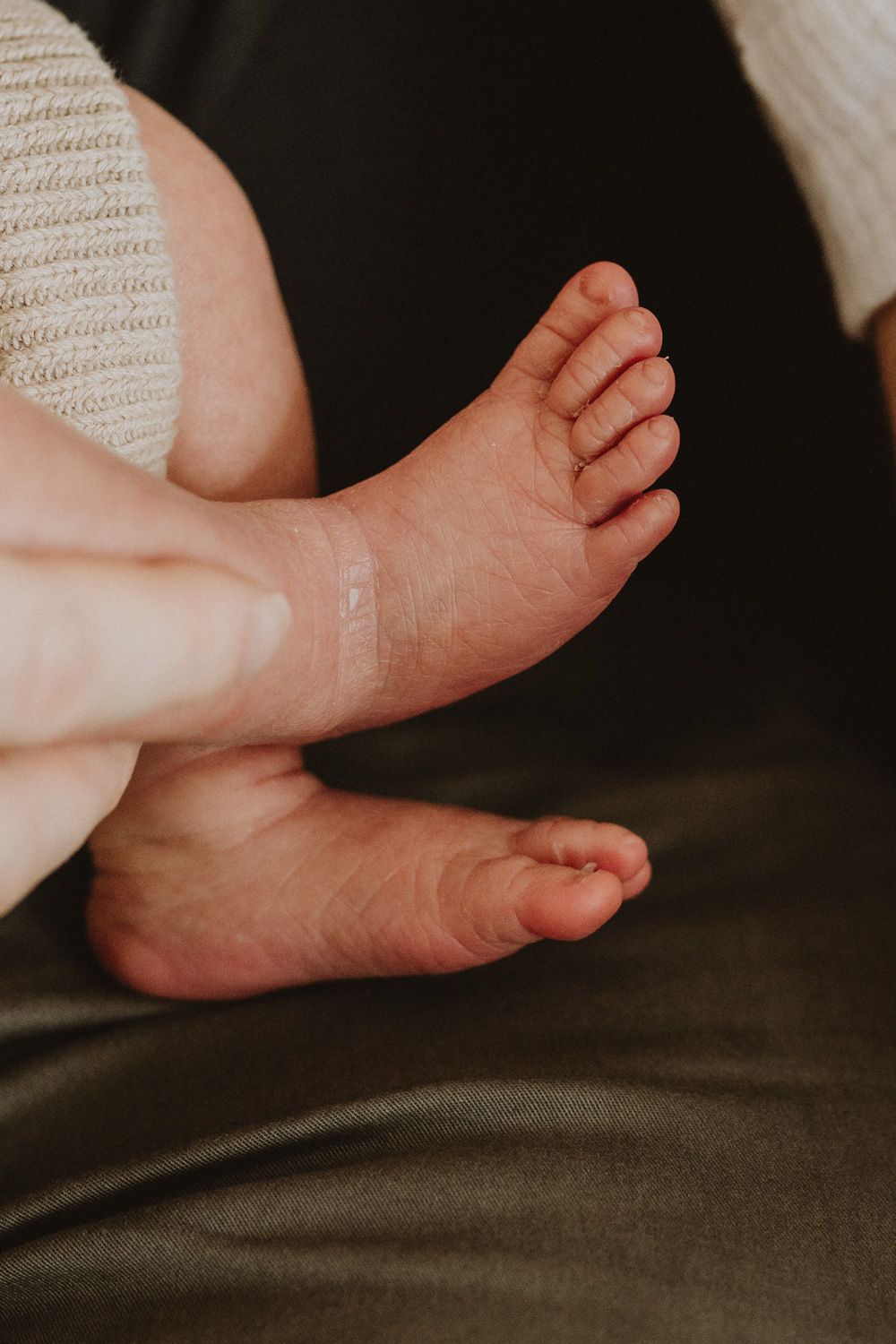 Close-up view of tiny baby feet against a dark background.