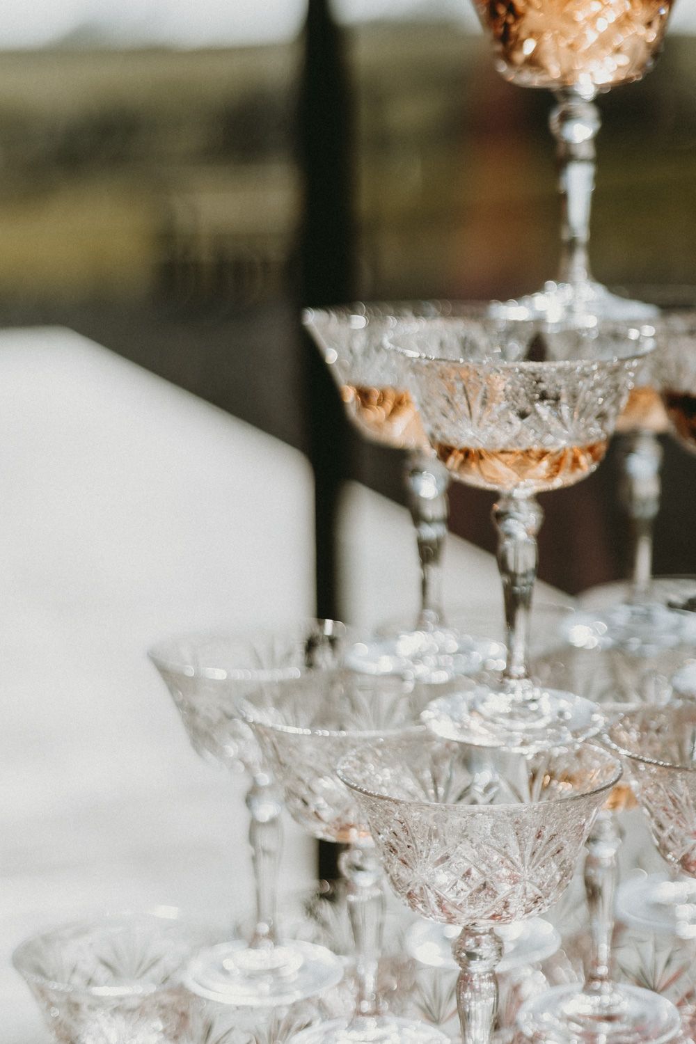Crystal champagne coupe glasses stacked in an elegant tower formation.