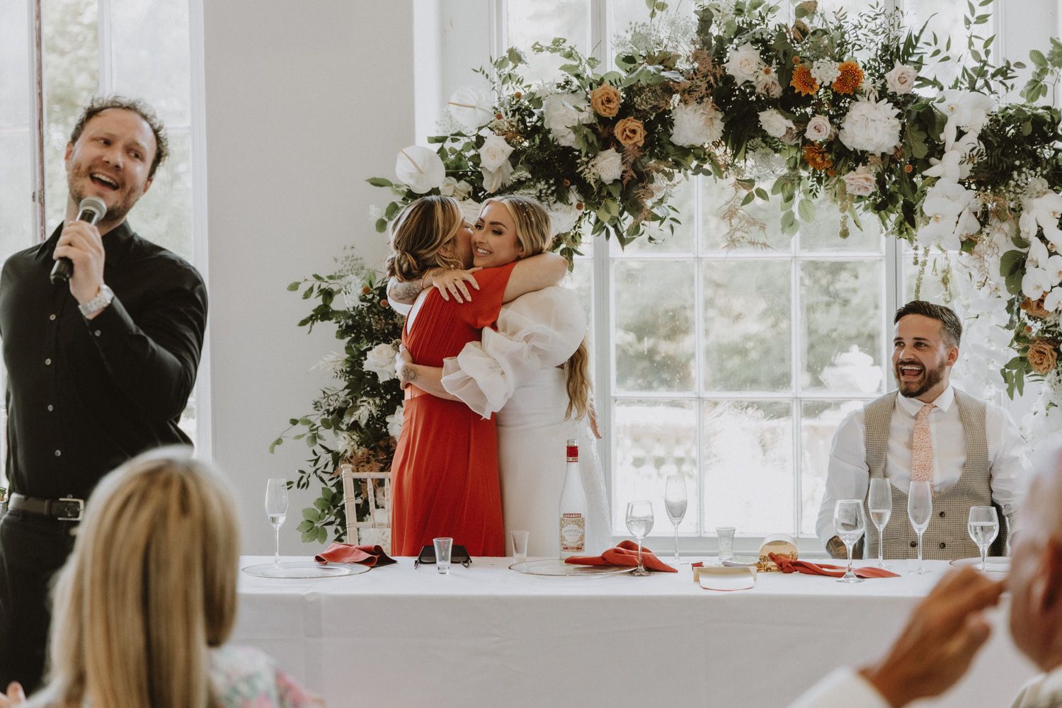 Wedding party celebrating at reception with elegant decor and floral arrangements.