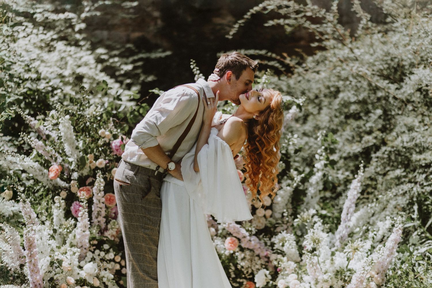 Romantic garden wedding photo with blooming white flowers and greenery.