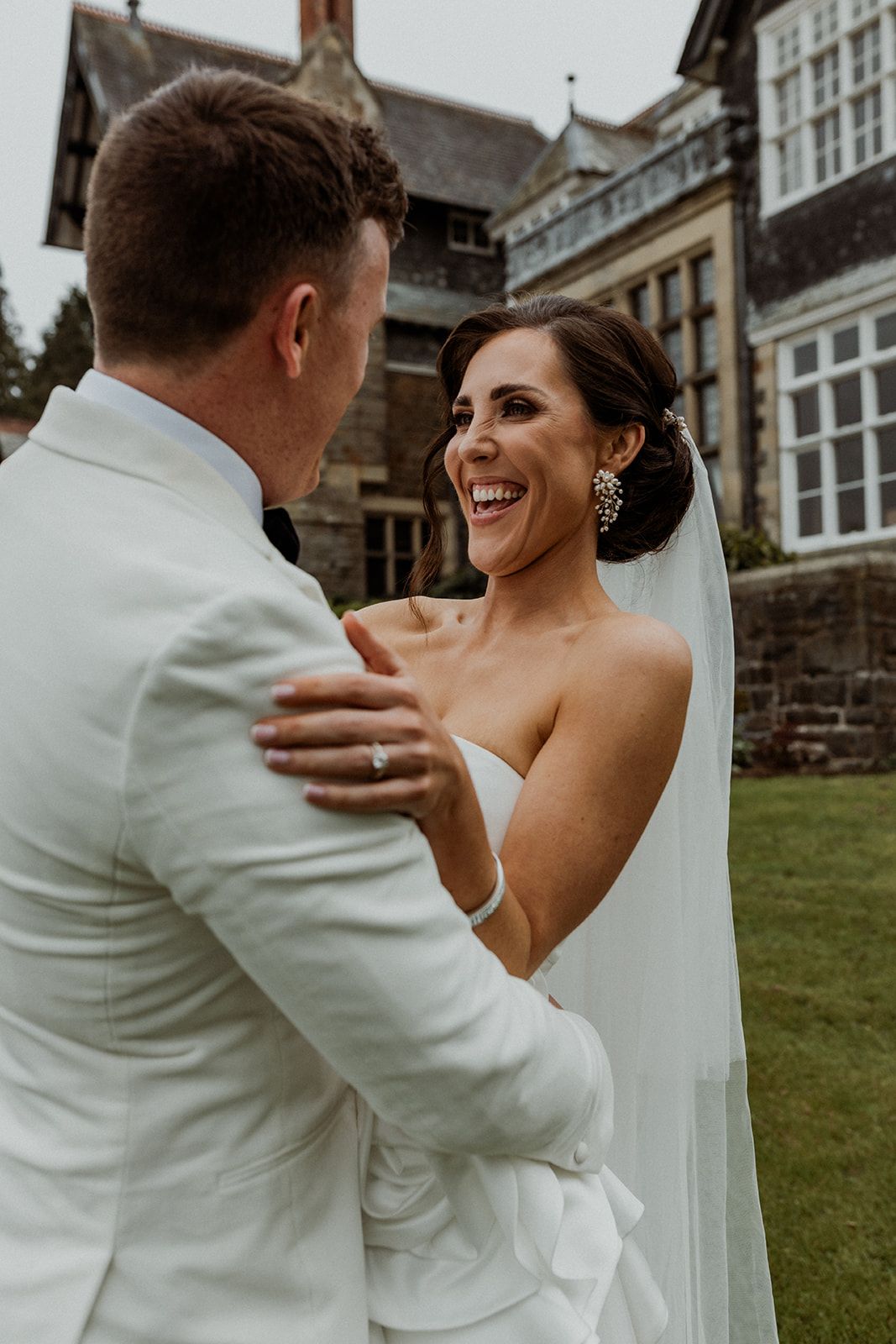 A joyful newlywed couple shares a candid moment together on their wedding day outside a grand historic building.
