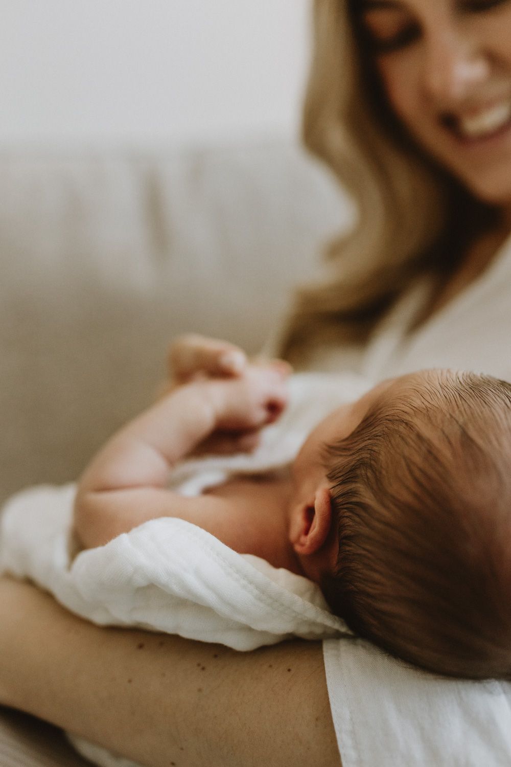 Intimate moment of mother nursing newborn baby in soft natural light.