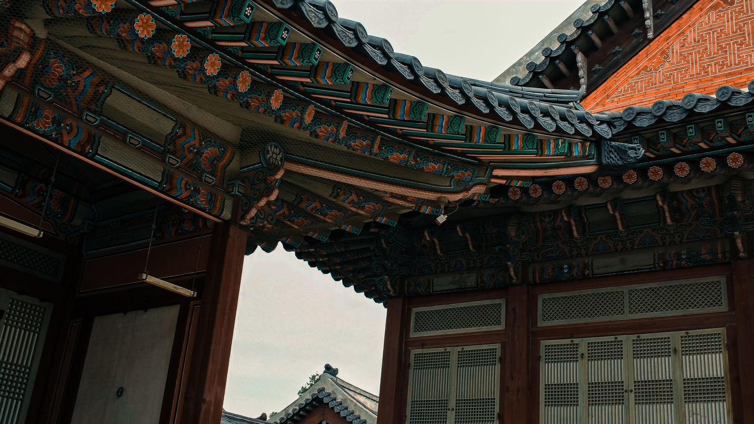 Traditional Korean temple architecture featuring ornate wooden eaves and detailed paintwork on the curved roof structure.