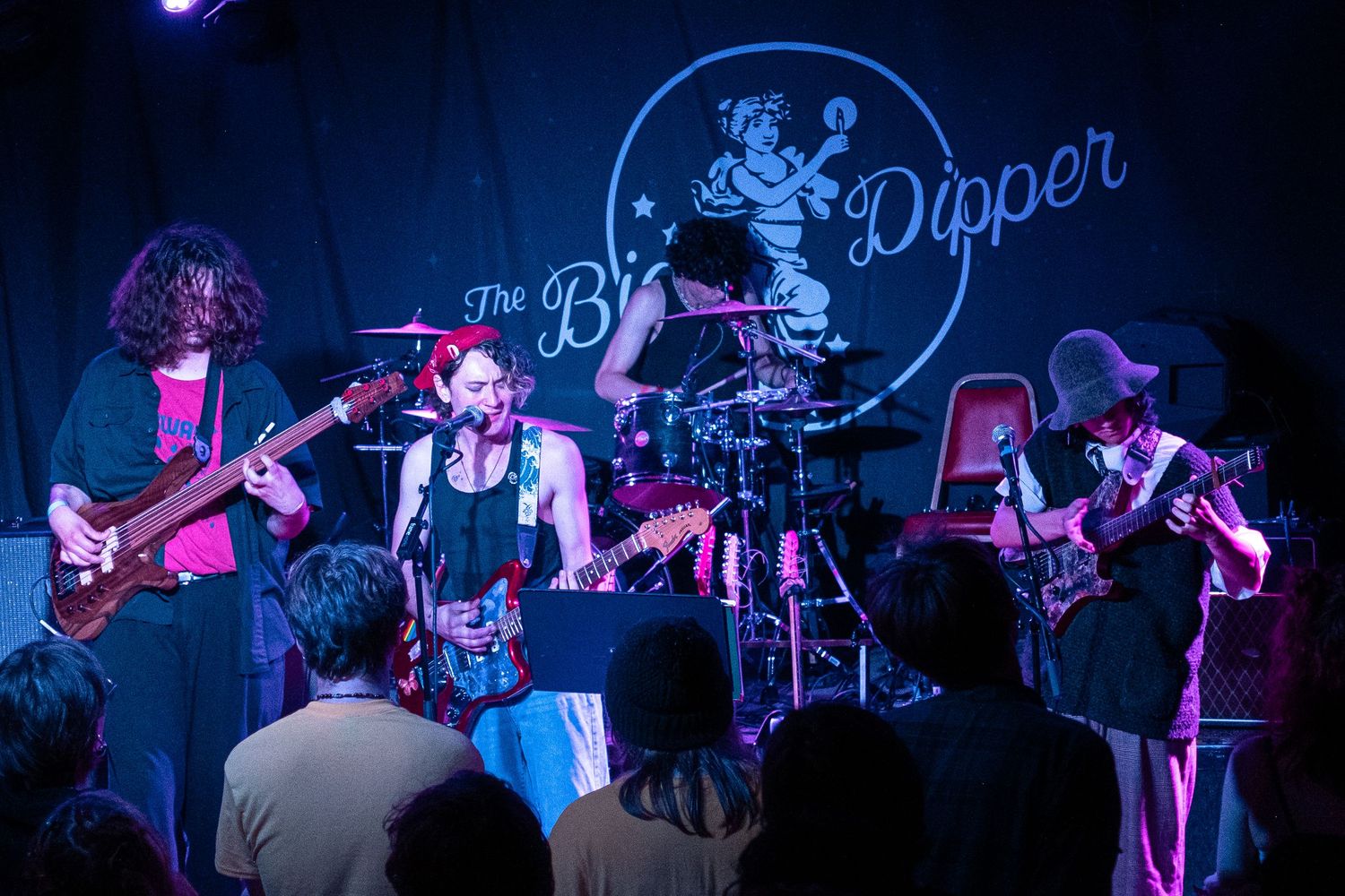 Rock band performs on stage with dramatic blue and purple lighting during an energetic live concert performance.