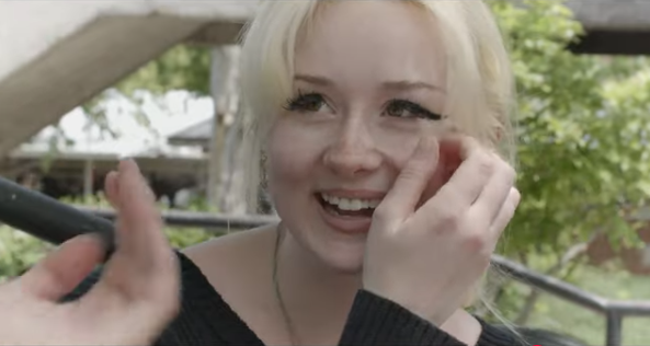 Person with blonde hair smiling  in natural light.