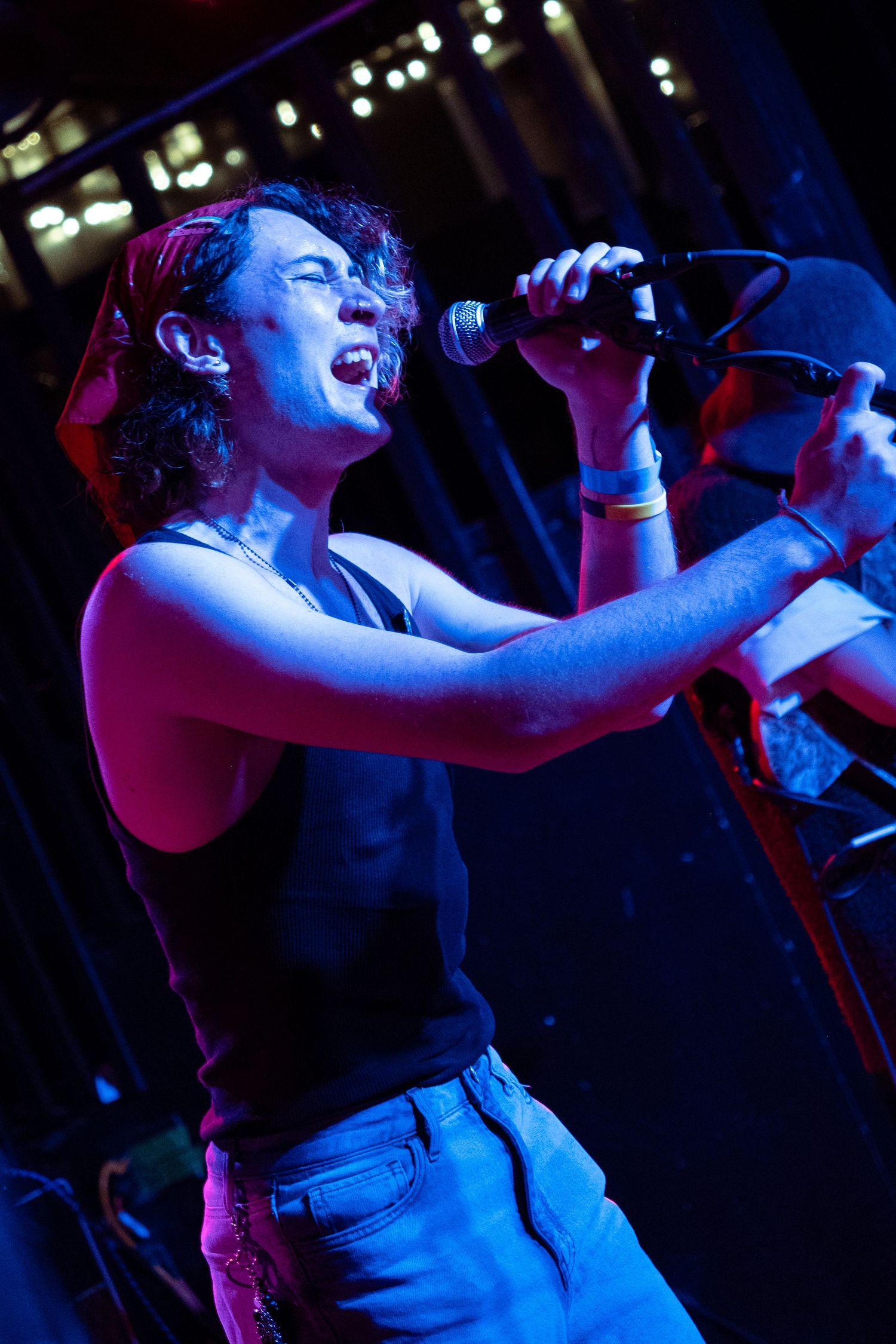 Performer sings passionately on stage under dramatic blue and purple lighting during an energetic concert performance.