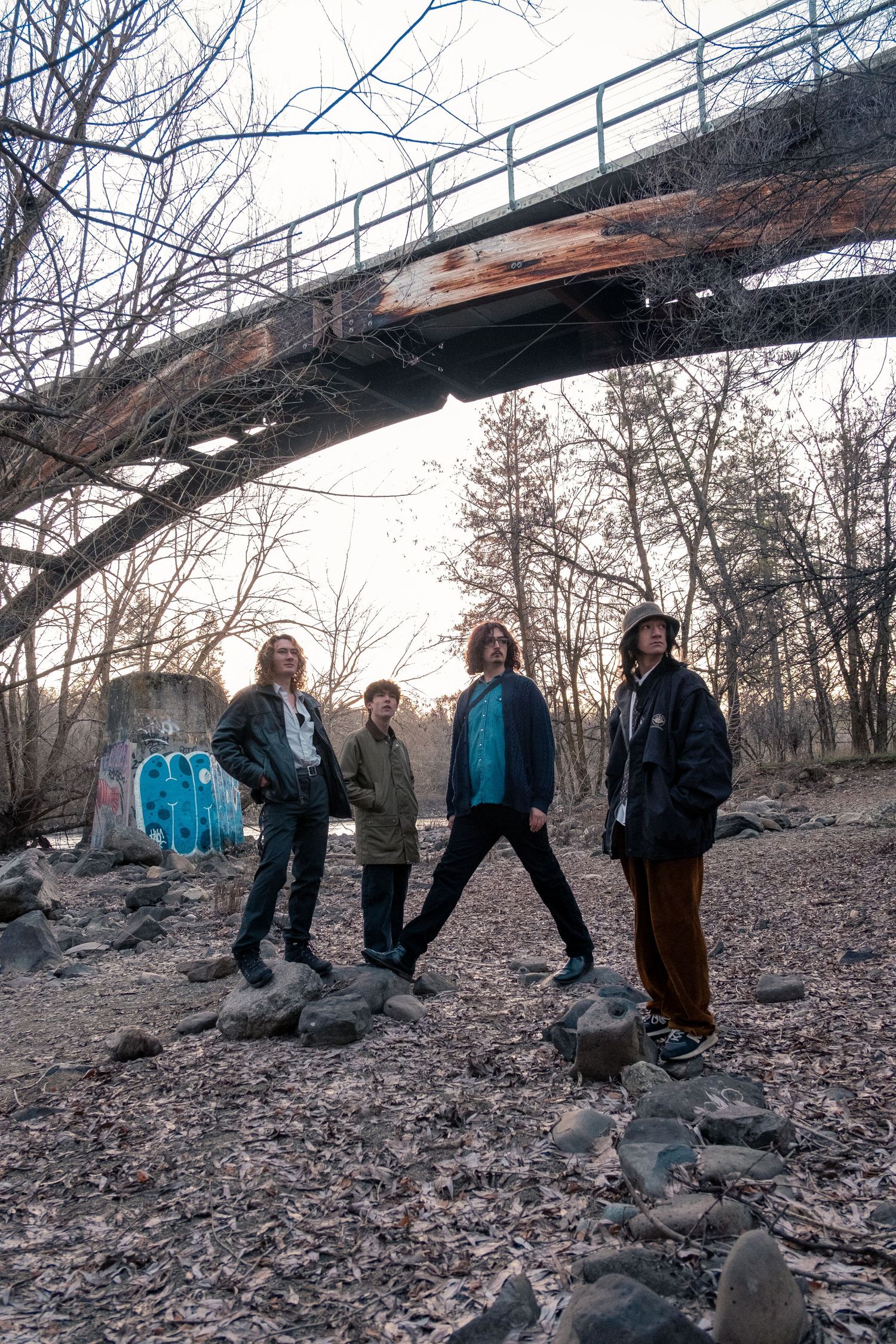 A group of people standing beneath a rustic bridge structure on rocky terrain during winter.