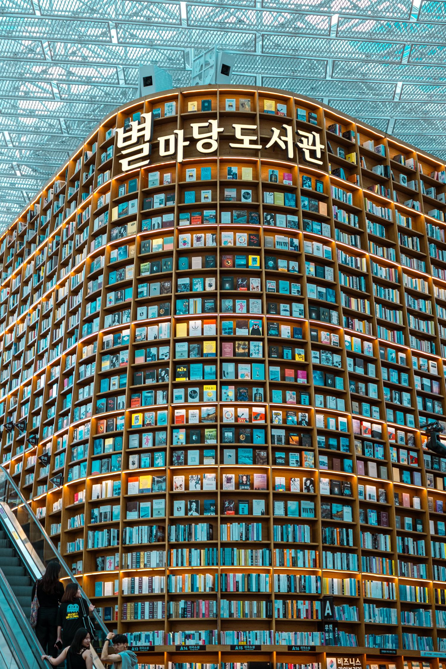Curved modern library building with illuminated shelves displaying thousands of books in Seoul, South Korea.