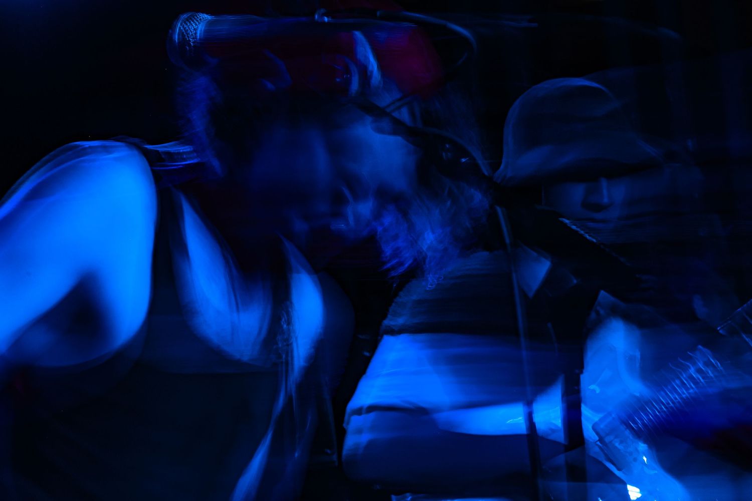Silhouettes of performers on stage illuminated by dramatic blue lighting during a nightclub performance.