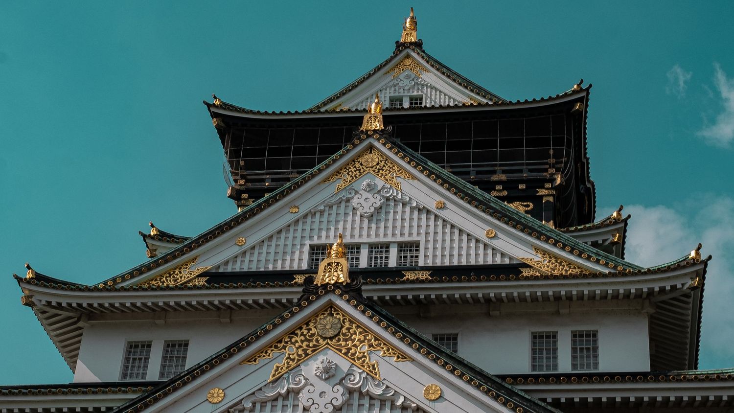 Colorful glass wind chimes hang against a traditional Japanese temple architecture backdrop with teal sky.