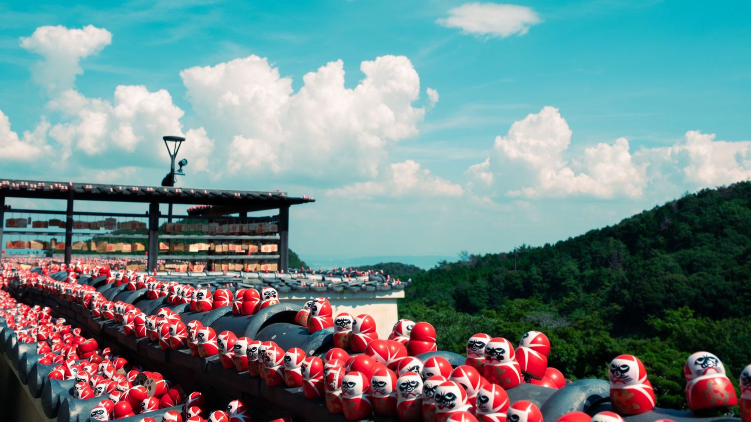 Panoramic view of a large crowd wearing red and white at an outdoor stadium event with mountains in the background.