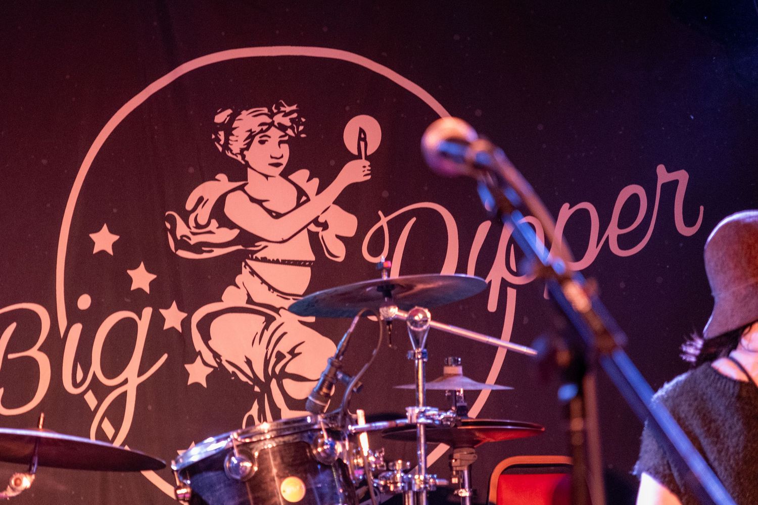 Neon cherub decorations illuminate a dark nightclub or bar setting with a pink and blue glow.