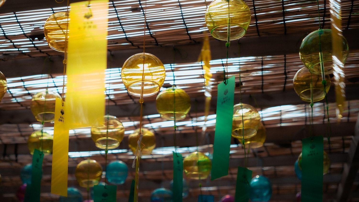 Yellow and green paper lanterns hanging from a bamboo ceiling create a festive outdoor party atmosphere.
