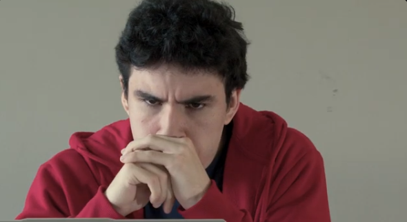 Person in burgundy sweater resting head on hands in deep thought.