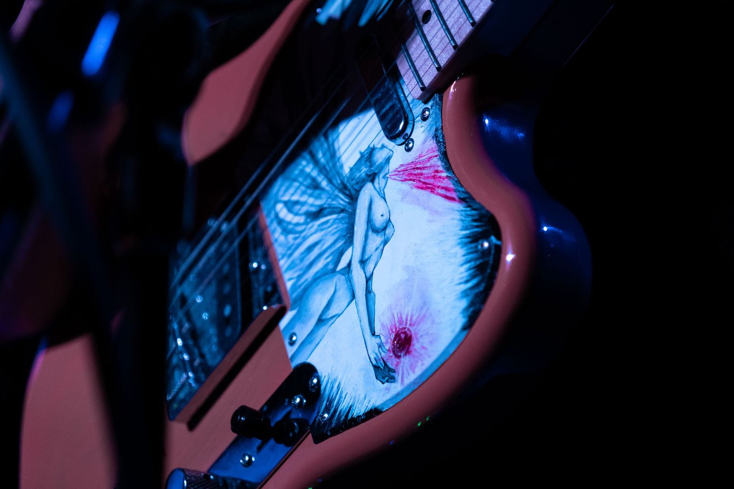 Close-up of hands playing electric guitar with dramatic blue and purple stage lighting effects.