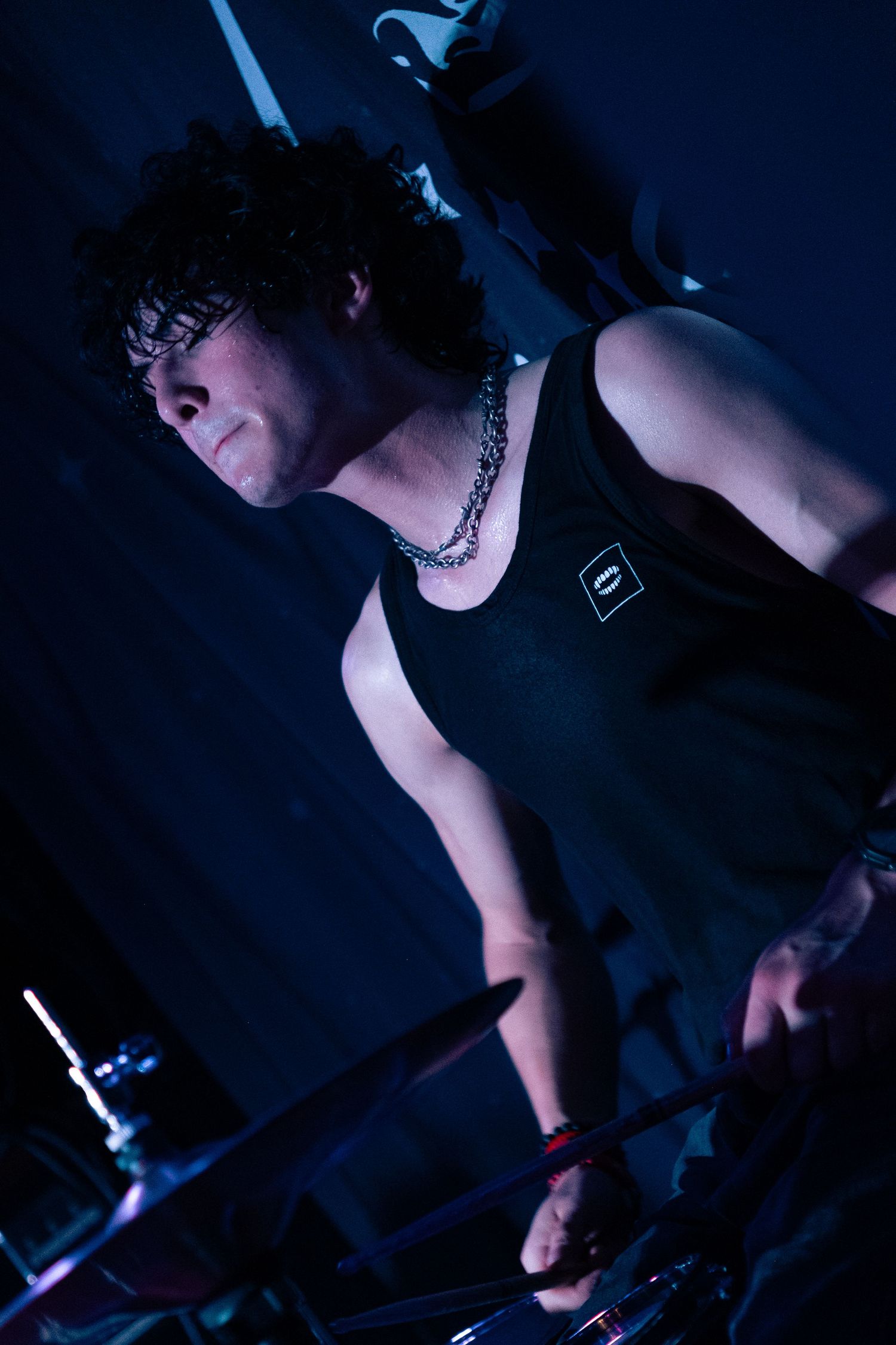 A musician performs in dramatic blue lighting while playing an instrument on stage during a live performance.