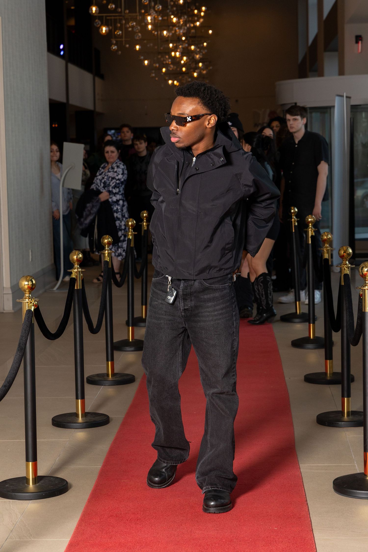 Event security personnel in black attire standing along red carpet with stanchion barriers.