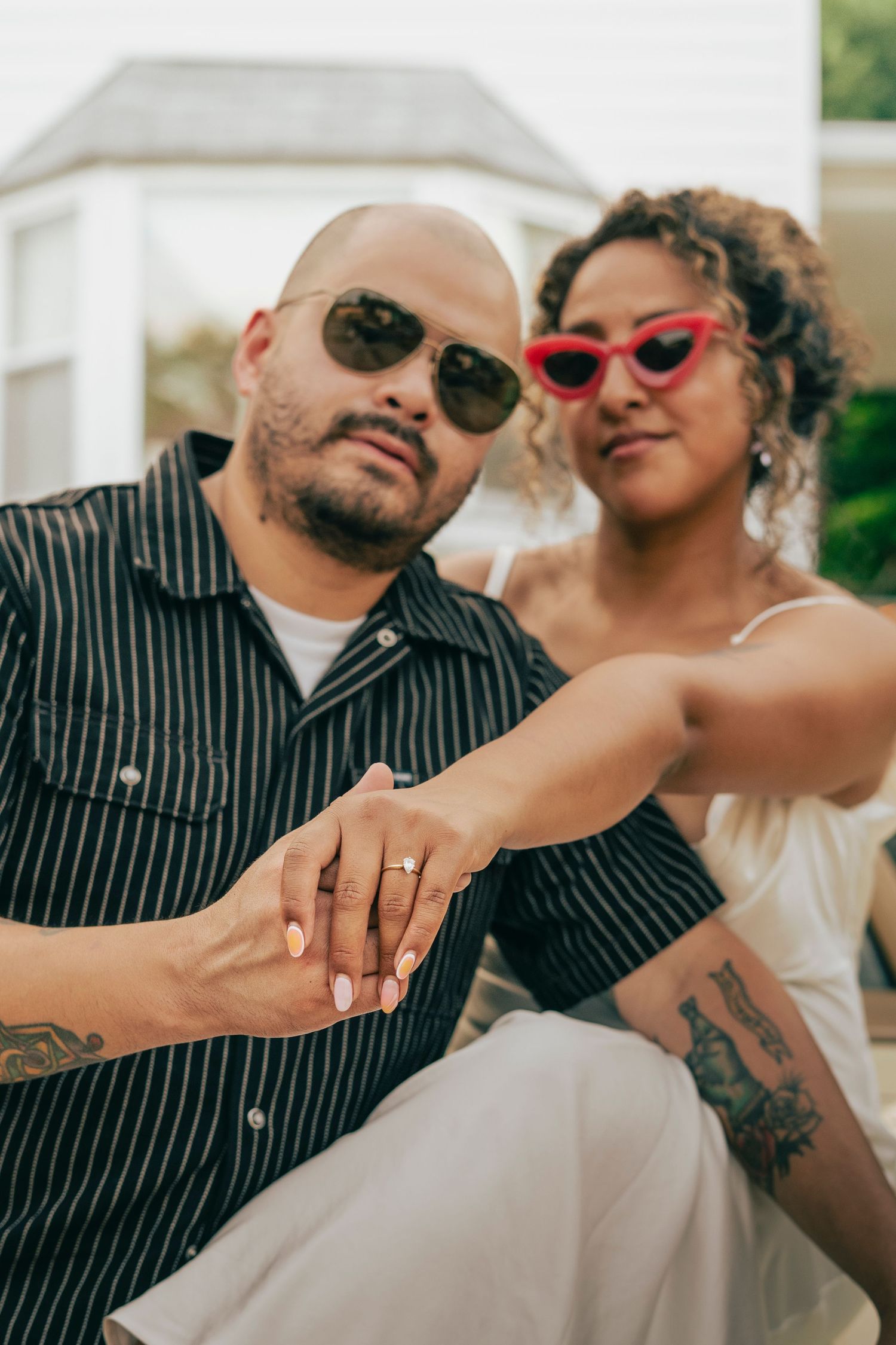A couple in sunglasses poses together showing off their engagement ring in a series of romantic photos.