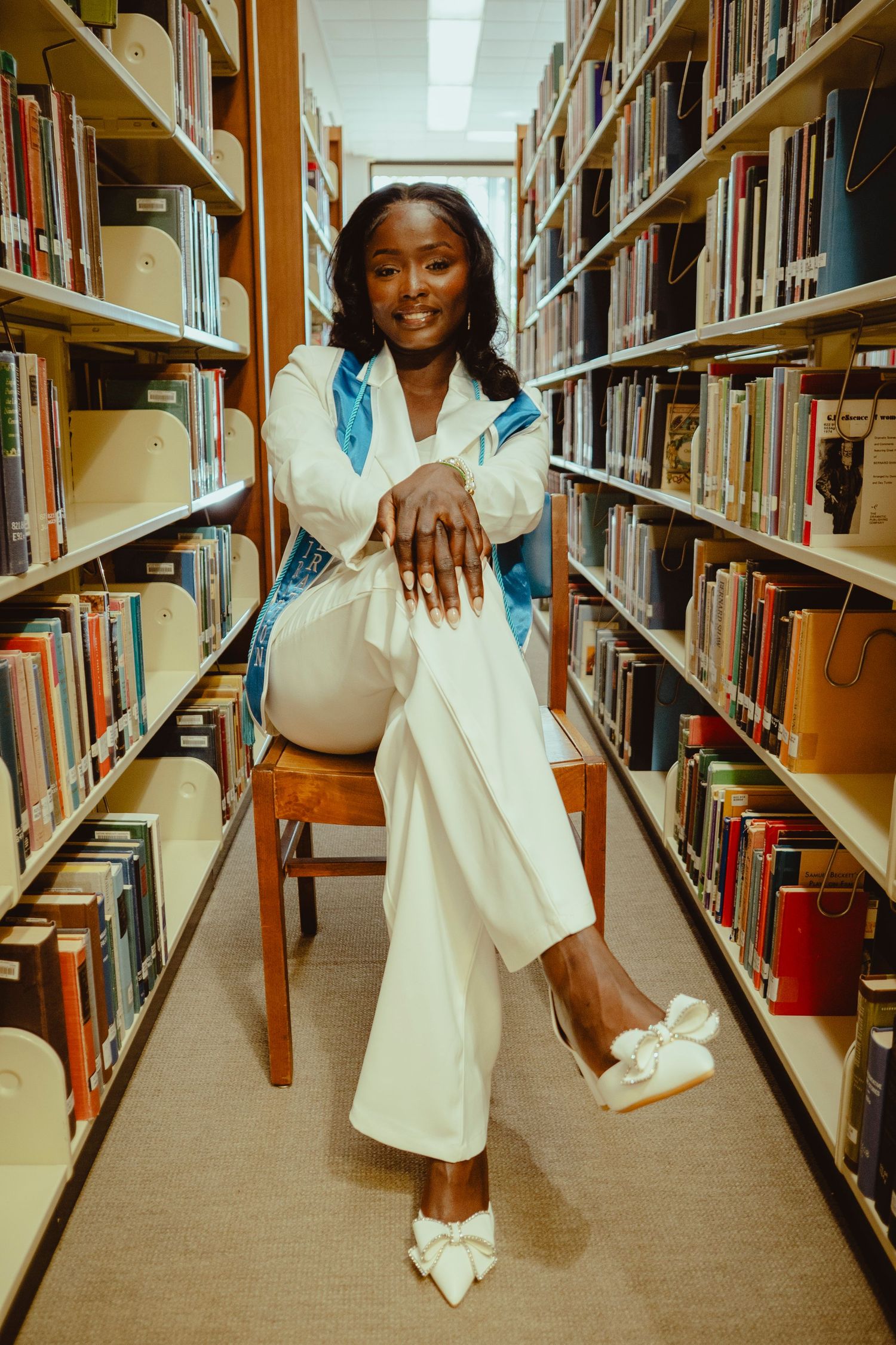 A person in a white dress poses playfully between library bookshelves in a sequence of connected photos.