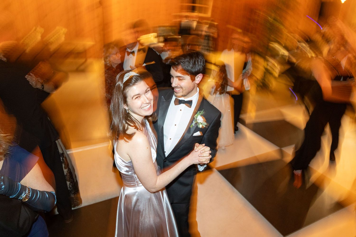 Couples dance together at an elegant indoor wedding reception with warm lighting and formal attire.