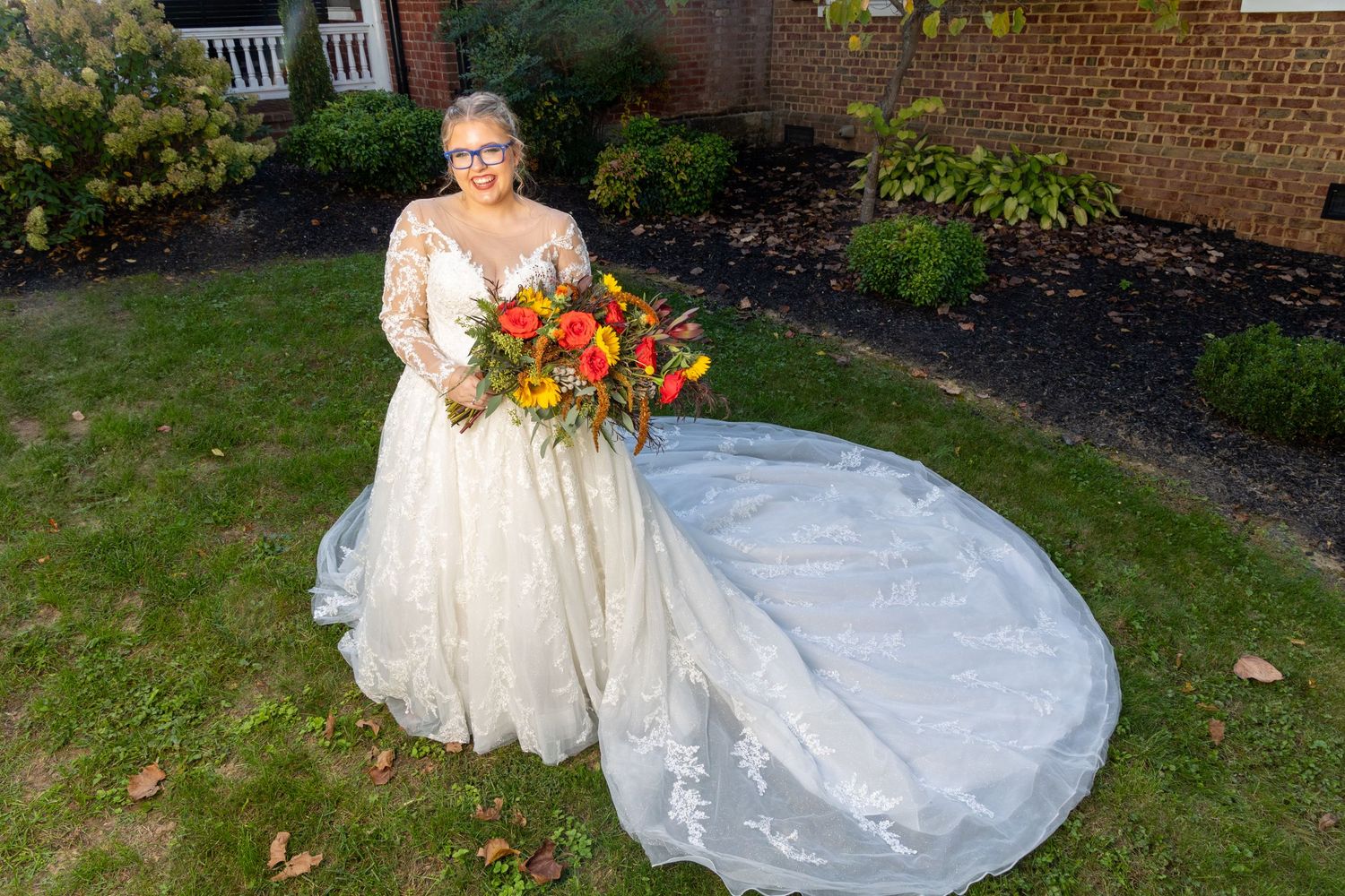 A beautiful autumn wedding scene with a flowing white gown and vibrant orange and yellow bouquet in a garden setting.