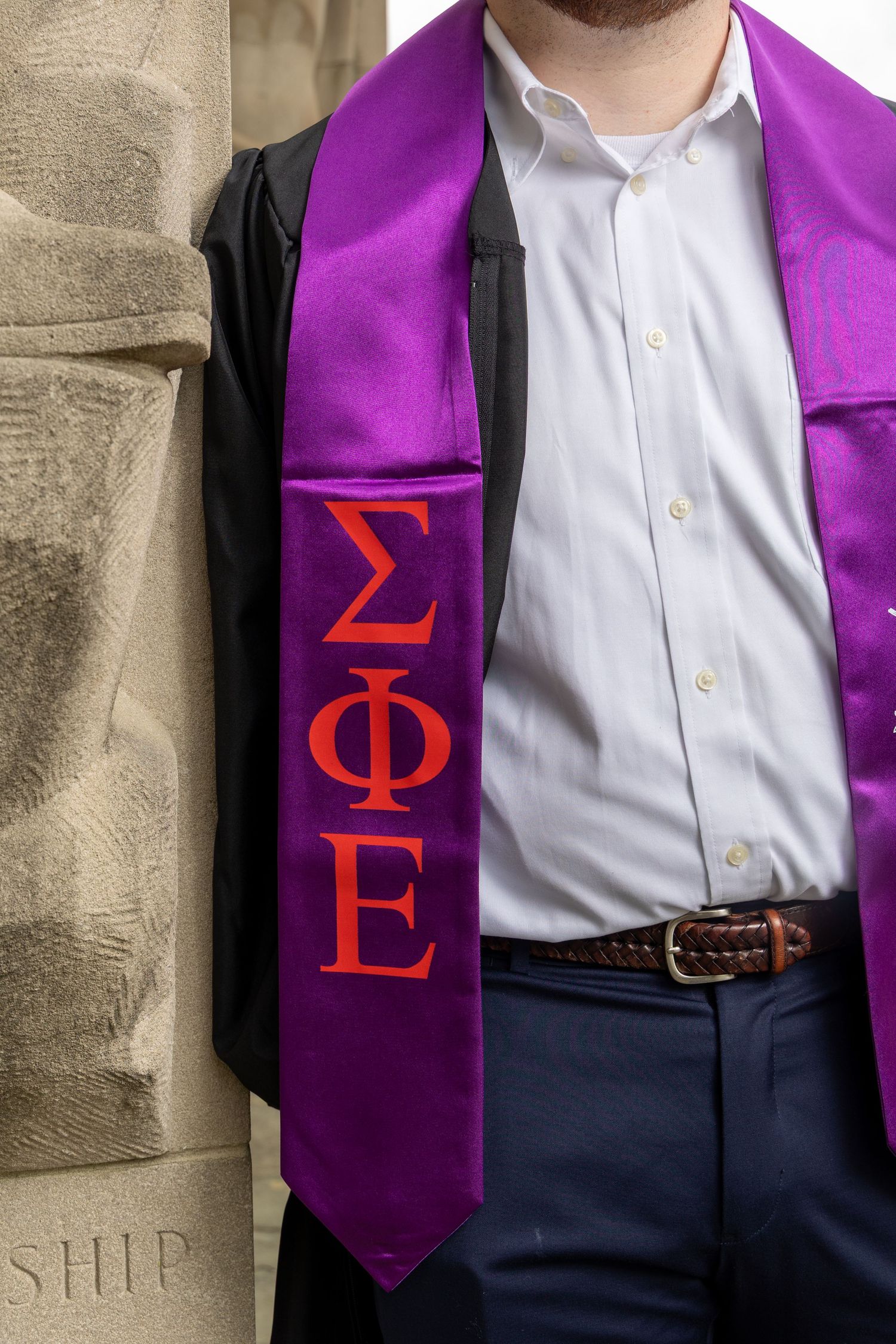 Purple graduation stole displaying Sigma Phi Epsilon Greek letters against formal attire.
