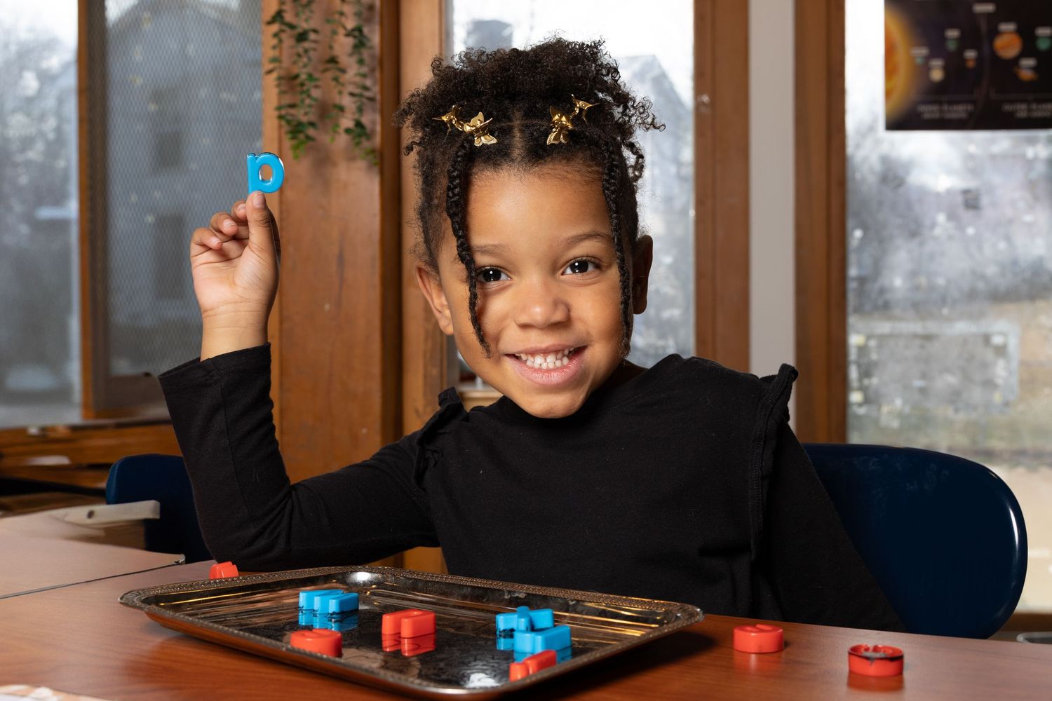 Child smiling and playing board game with colorful pieces.