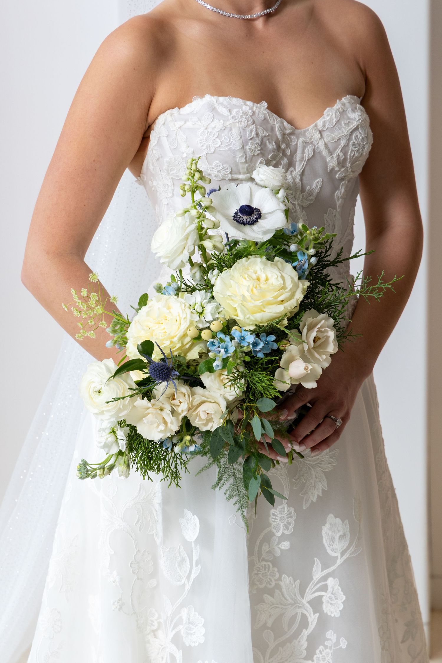 A white bridal bouquet with roses, anemones, and blue accents shown in five progressive angles against a white background.