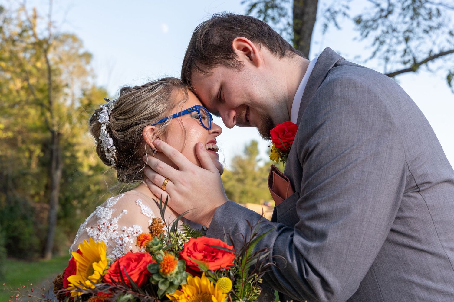 A couple shares intimate moments in an outdoor fall setting with colorful autumn bouquets and formal attire.
