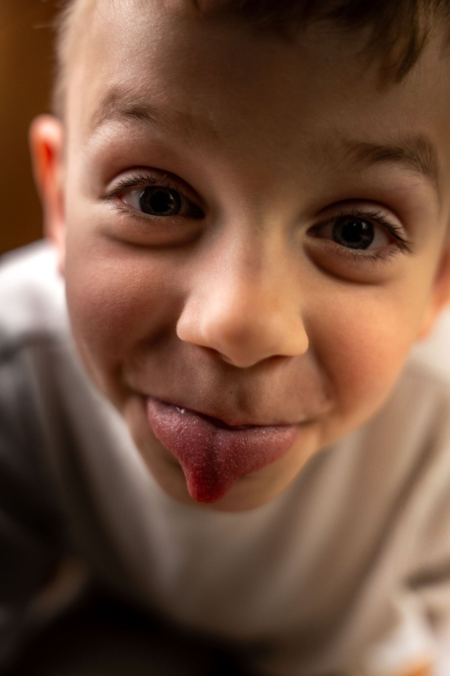 A playful young boy sticking his tongue out and smiling mischievously at the camera.