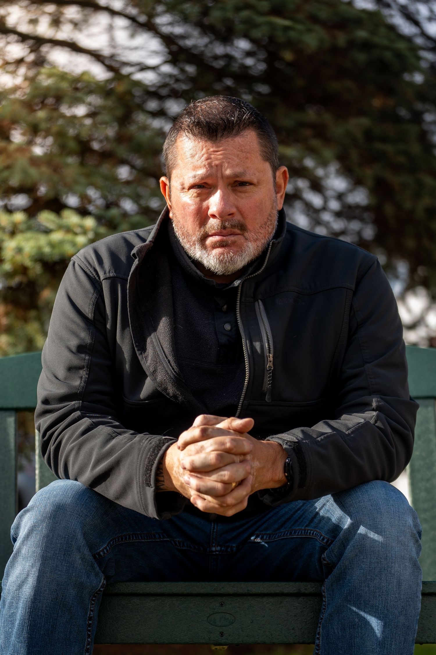 Person in black clothing sits thoughtfully on a green bench outdoors, shown from multiple angles in a photo series.