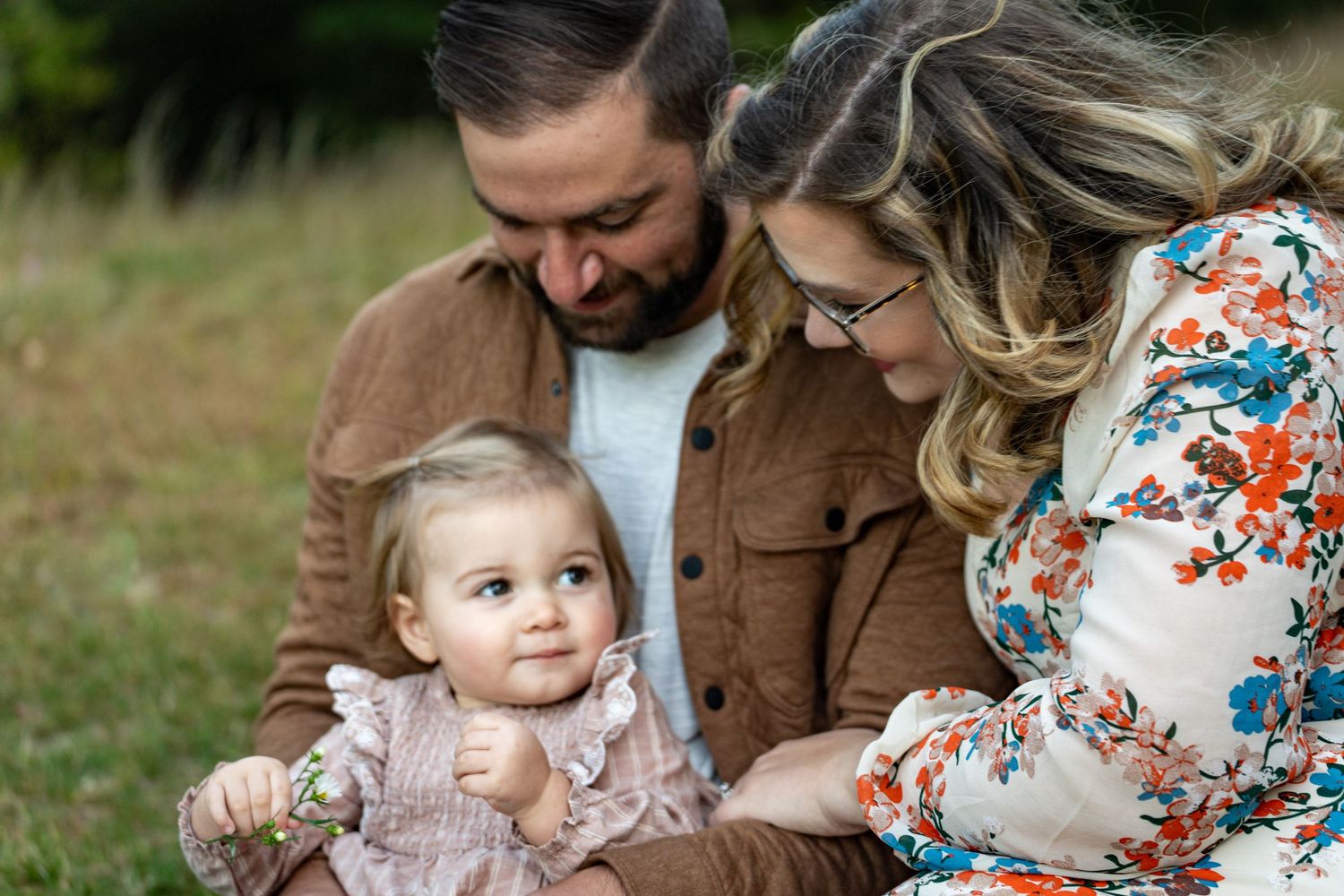A tender outdoor family moment captured in soft natural lighting during a maternity photo session.