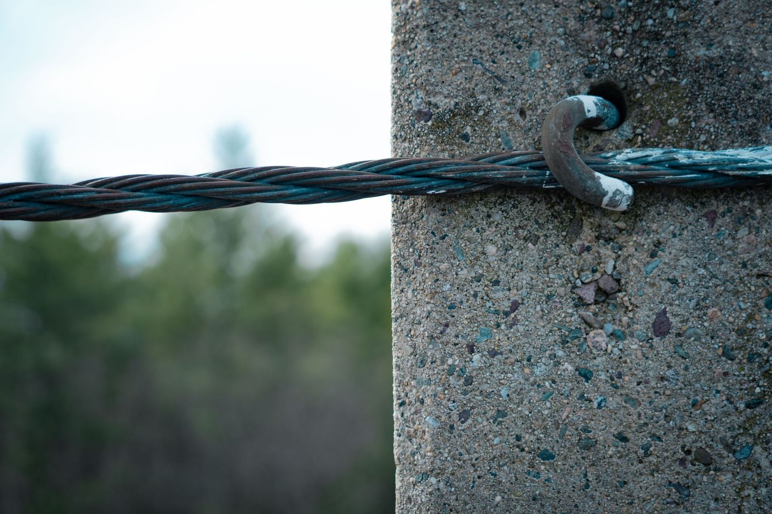 Closeup view of a black cable or wire running across a textured concrete surface with a blurred background.