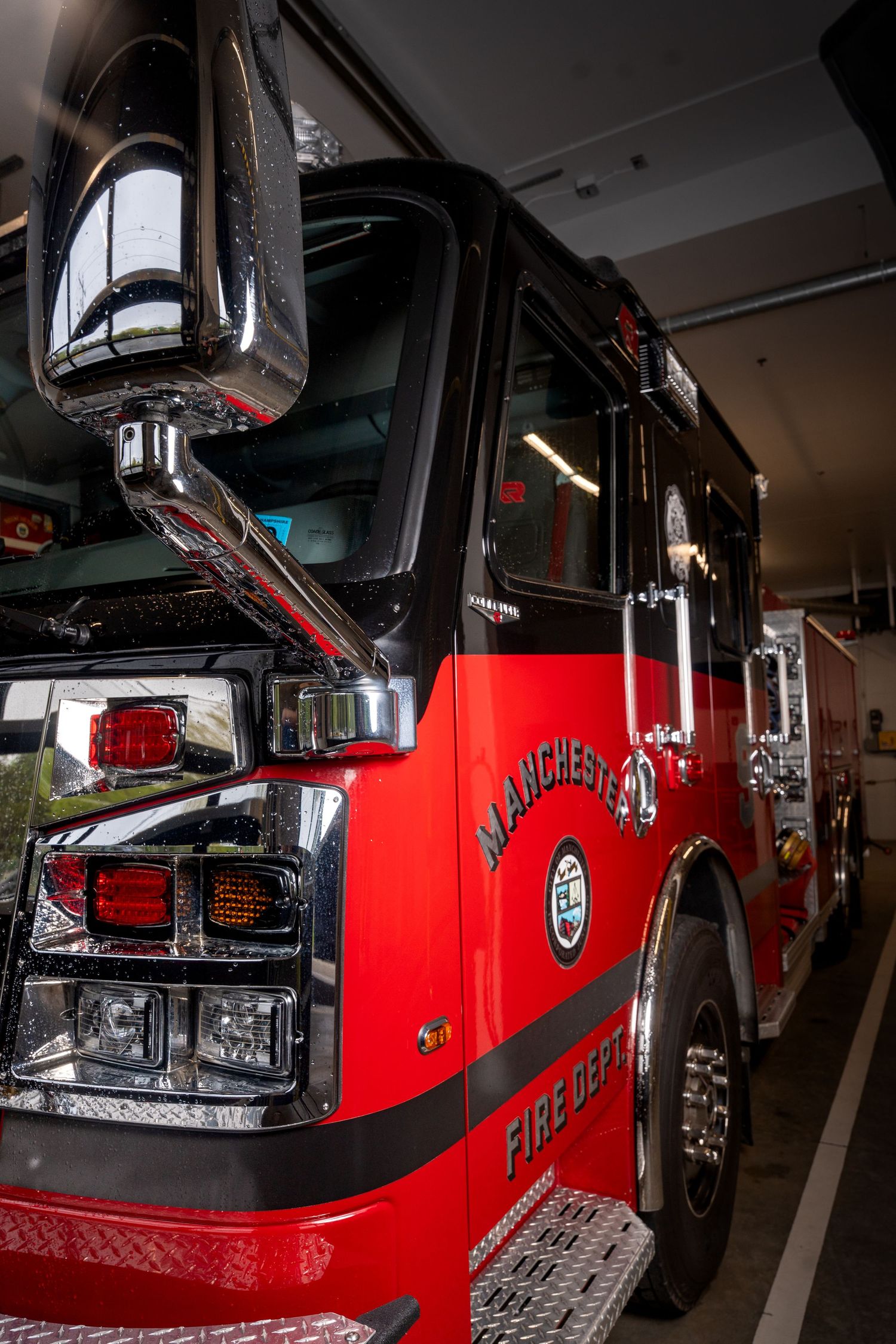 Manchester Fire Department red fire truck parked inside a fire station garage.