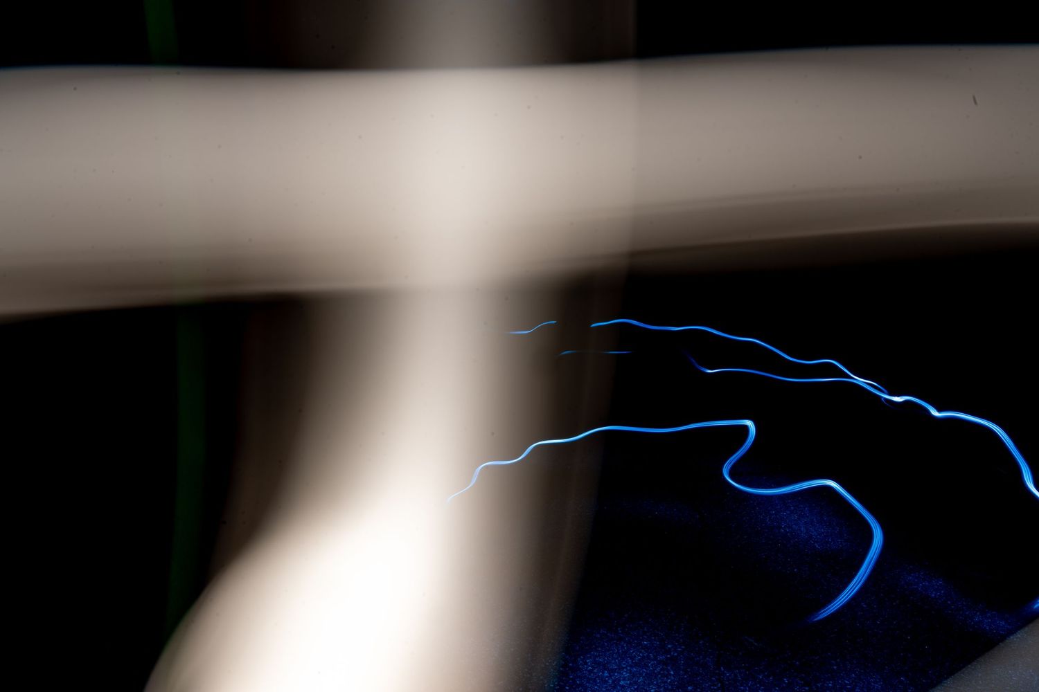 Blue electric lightning bolt light painting captured in long exposure photography against a dark background.