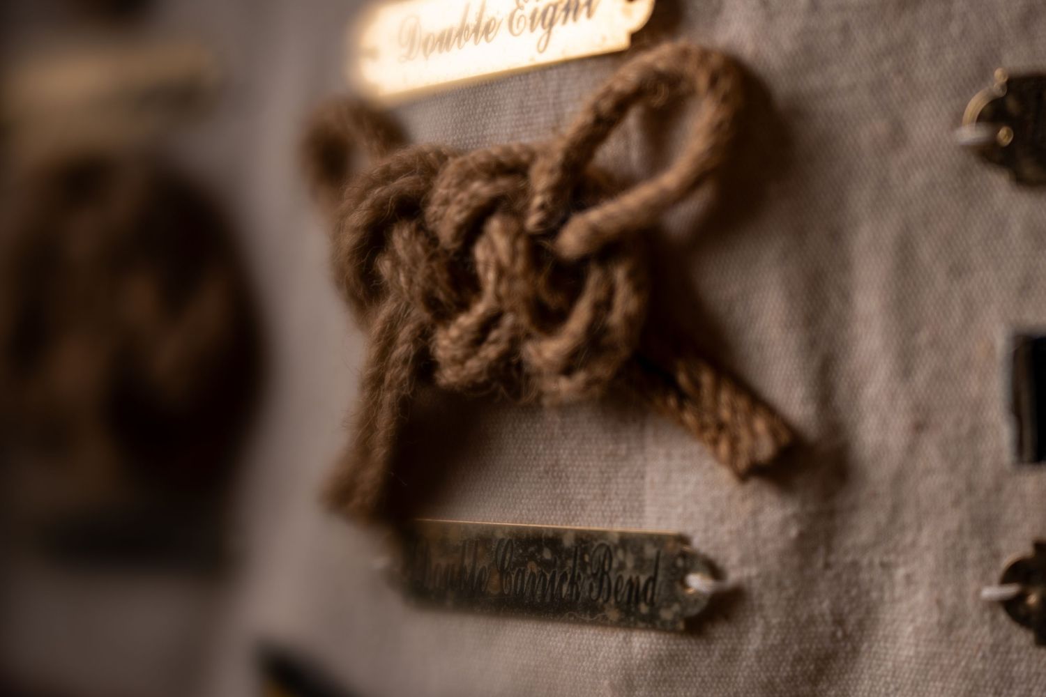 Close-up of a decorative rope knot labeled Double Eight on a fabric display board with metal accents.