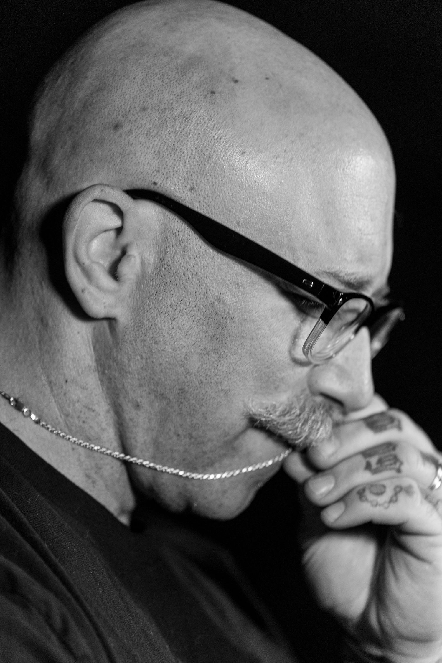 Black and white profile portraits showing a bald person with glasses in contemplative poses.
