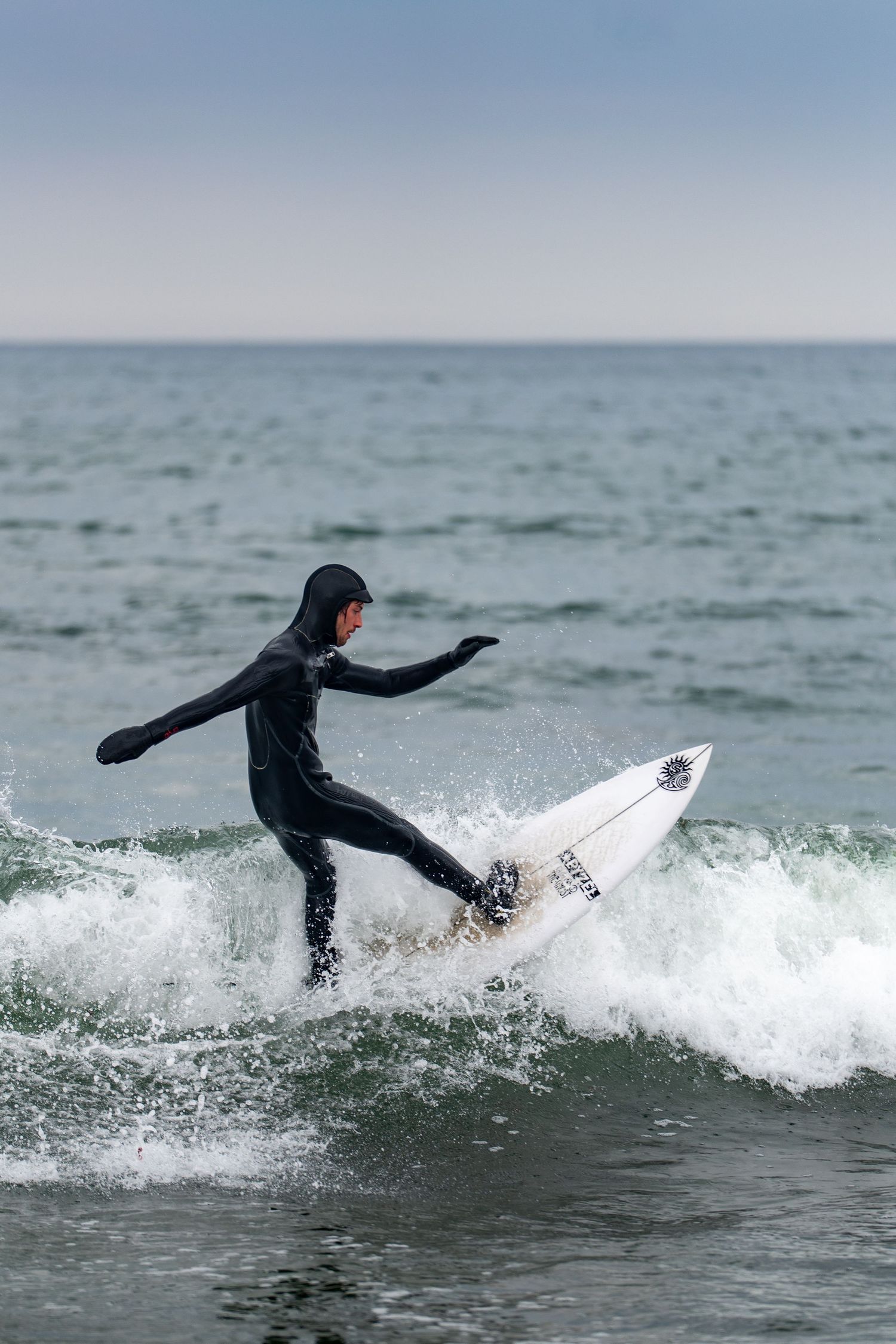 Surfer in black wetsuit riding a white surfboard on ocean waves.