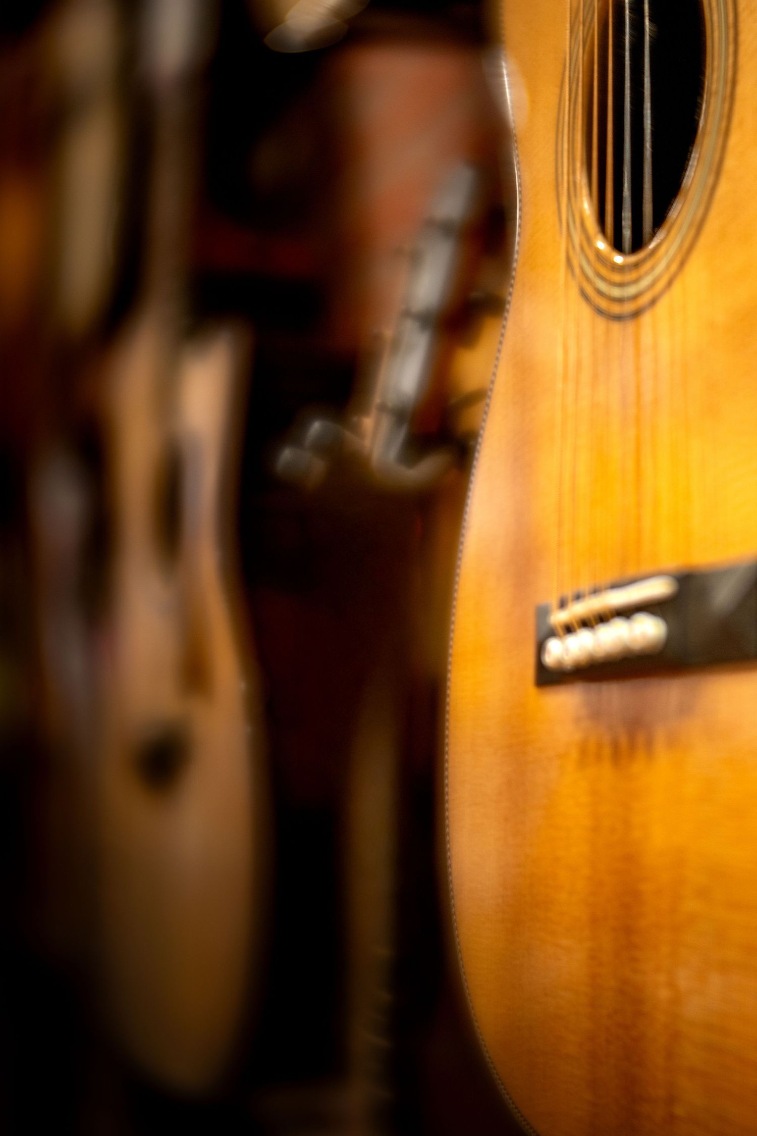 Vintage acoustic guitar with warm honey finish displayed among a collection of guitars in a music shop.