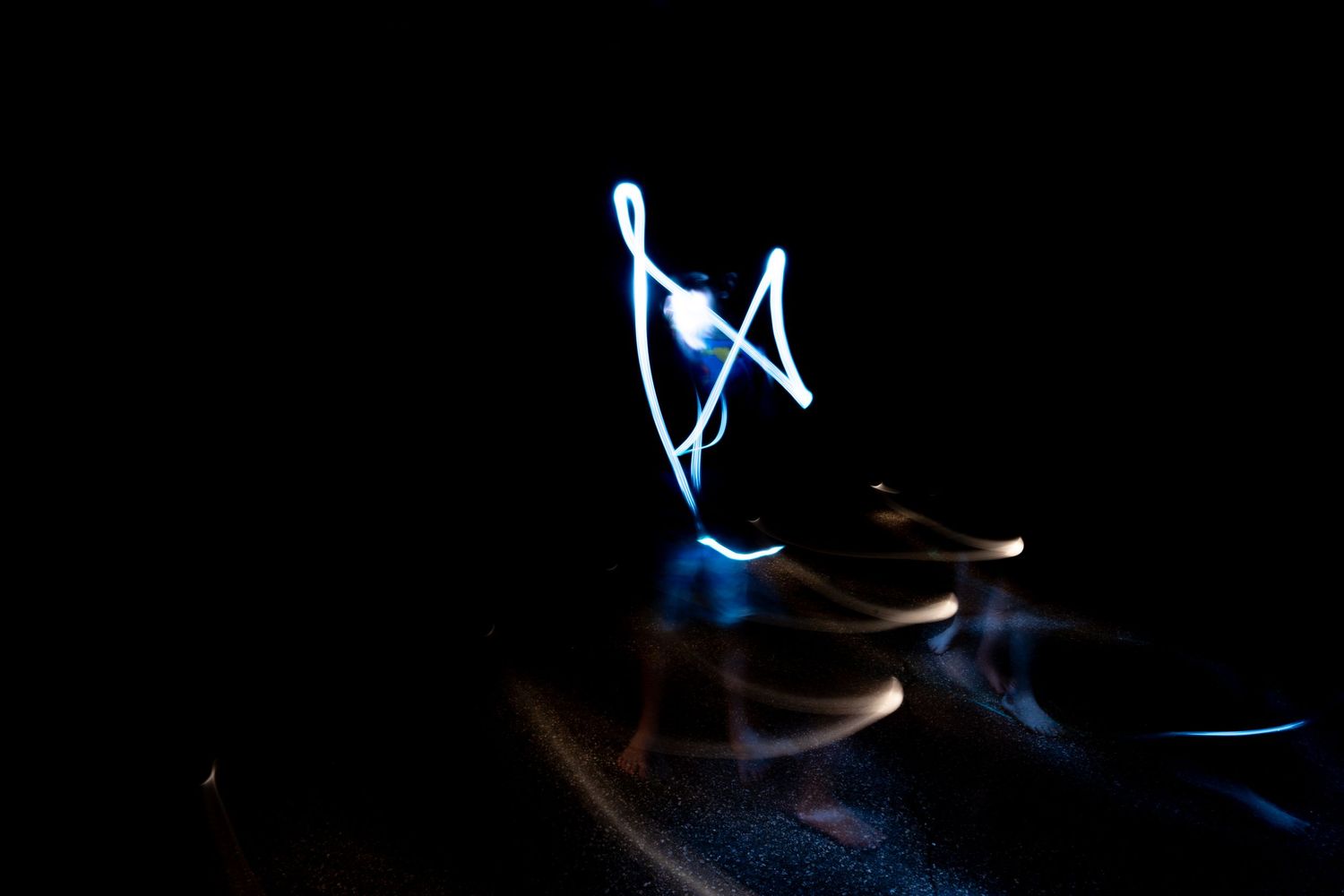 Blue light painting swirls against a dark background with glowing shapes.