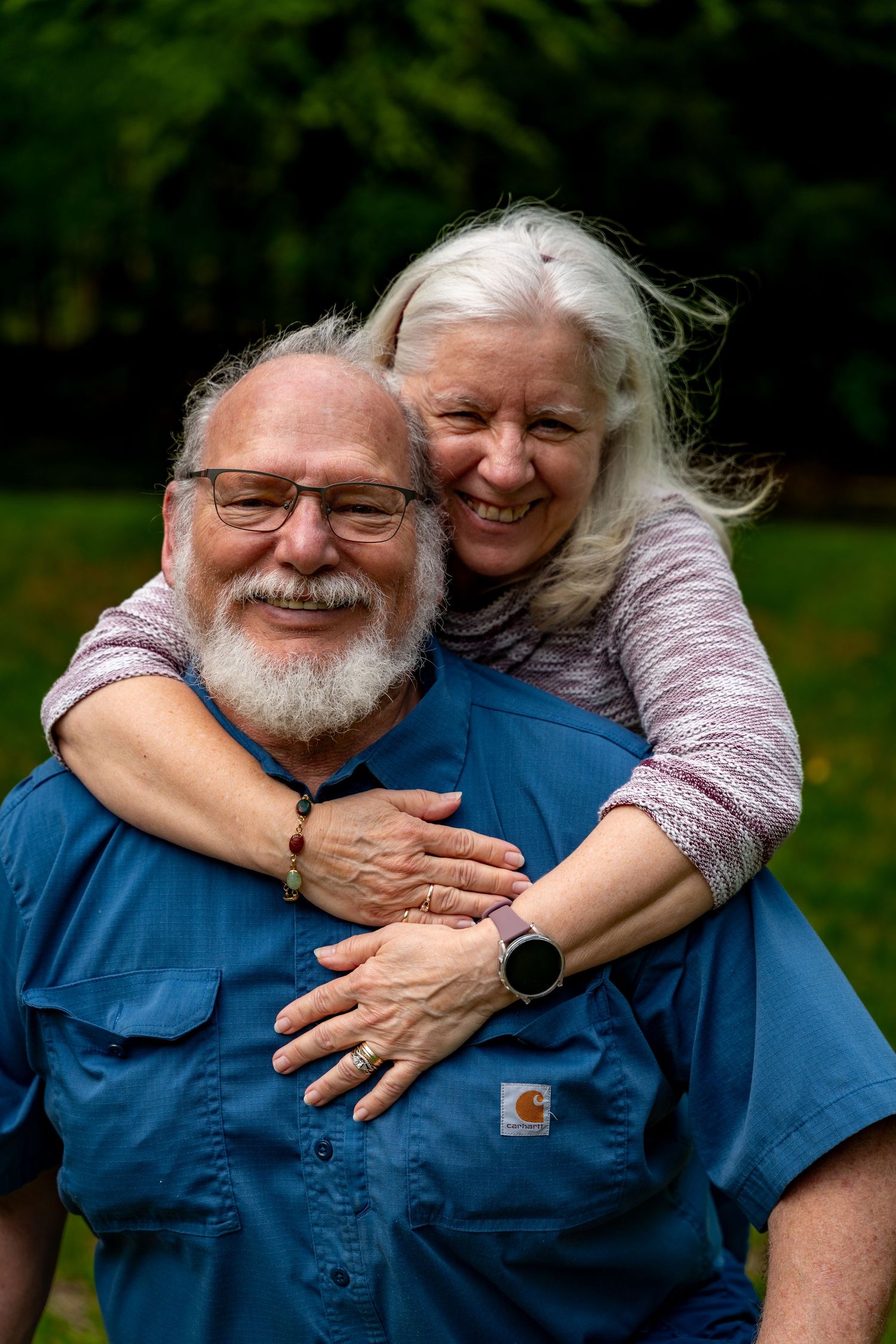 A loving couple embraces outdoors, sharing joyful laughter and genuine affection in a natural setting.