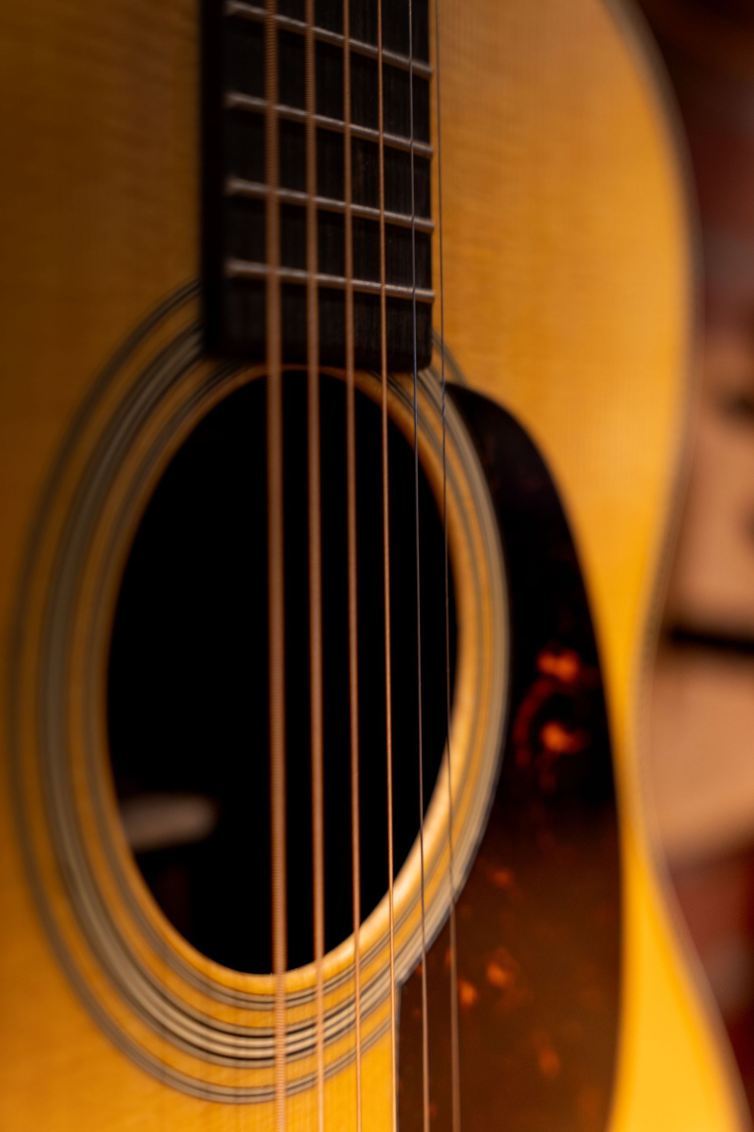 Close-up of an acoustic guitar soundhole and strings with warm golden lighting highlighting the wood grain.