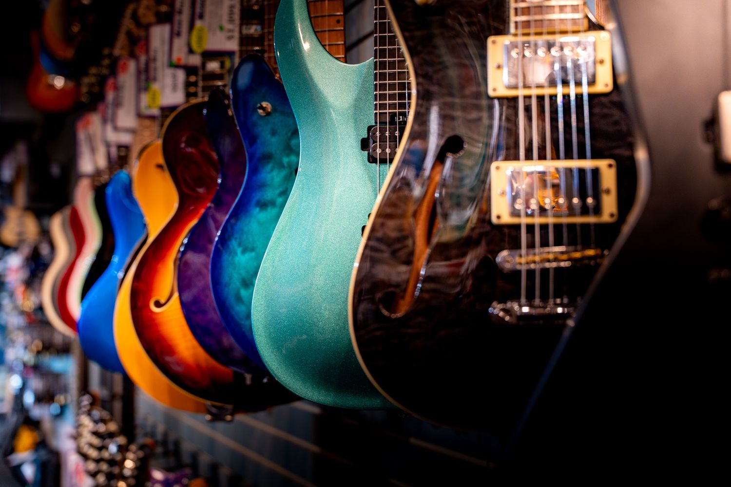 Colorful collection of electric guitars displayed on a wall in a music store.