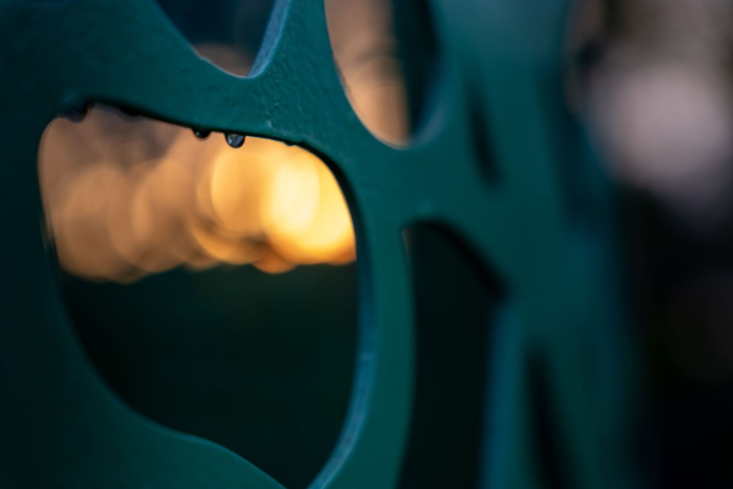 Close-up of a teal film reel with a golden bokeh background, capturing vintage cinema nostalgia.
