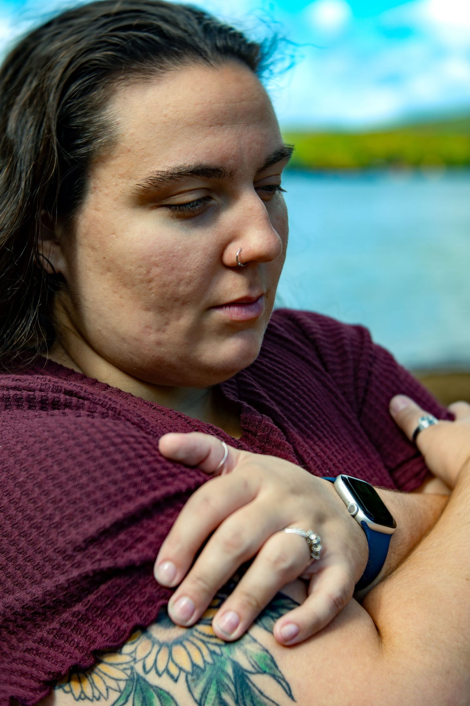 Close-up view of colorful tattoo artwork on shoulder with burgundy sweater visible in frame.