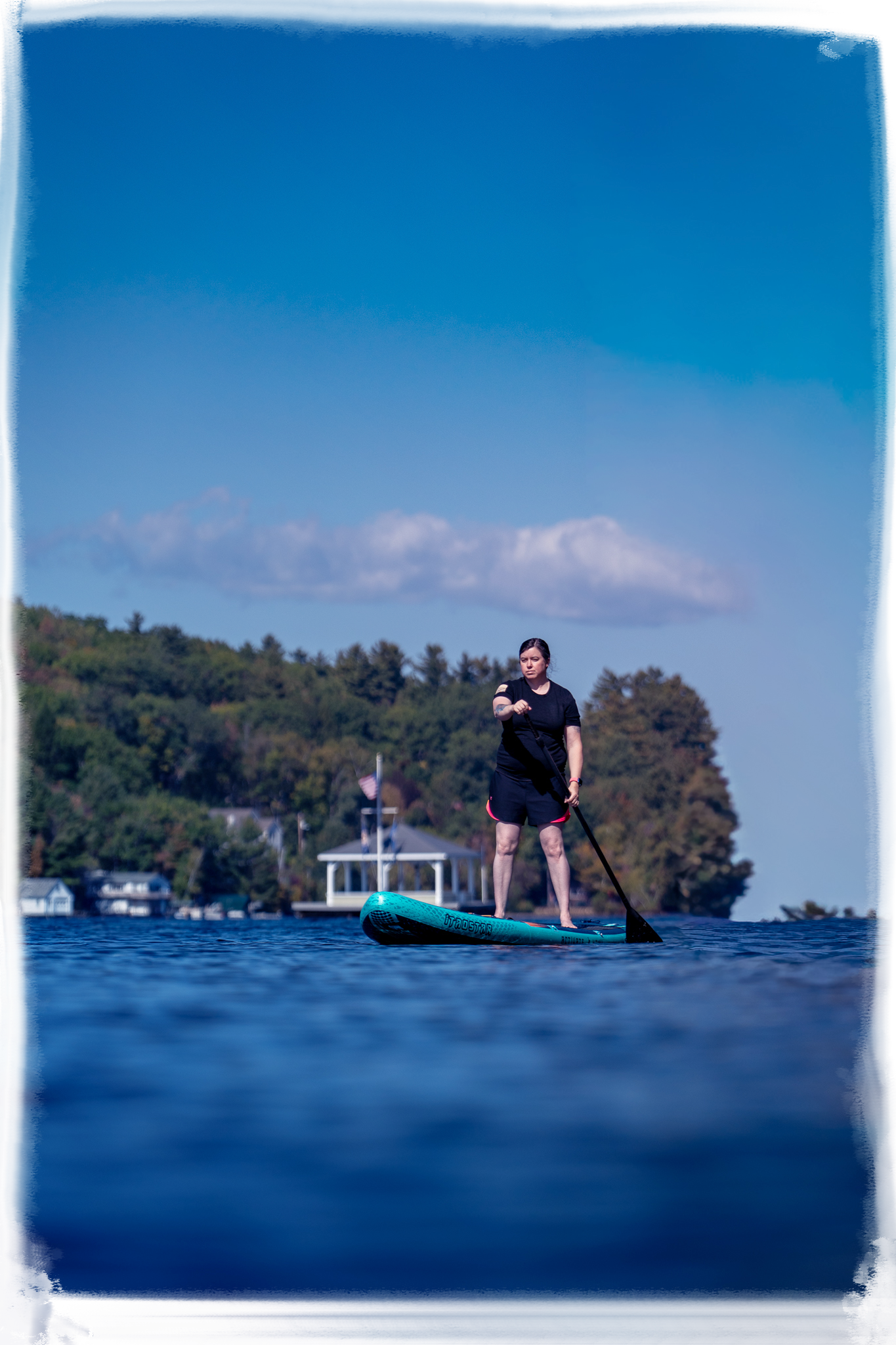 Series of blurry photos showing a kayak on a calm blue lake with trees and buildings along the shoreline.